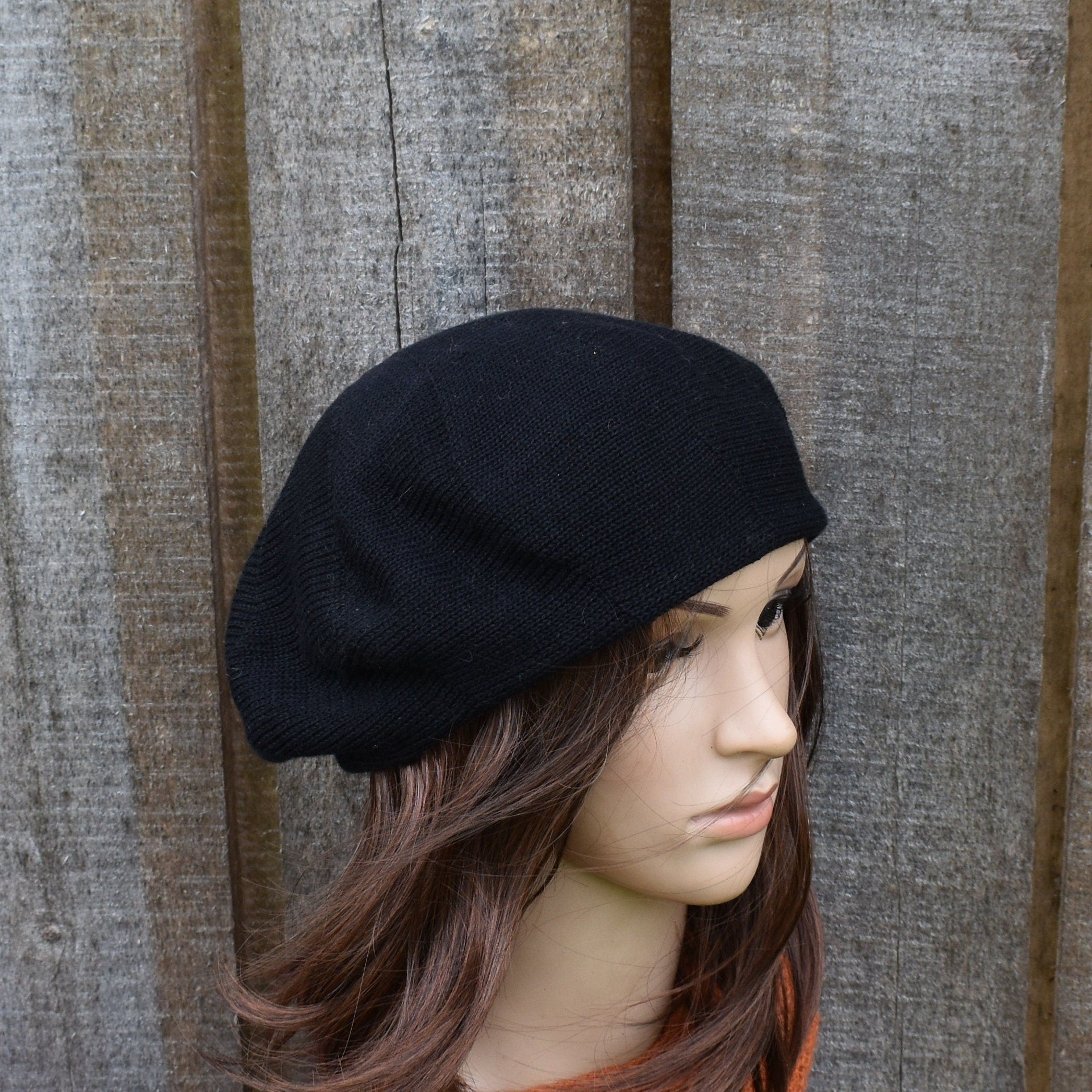 Black beret on a mannequin head against a wooden background