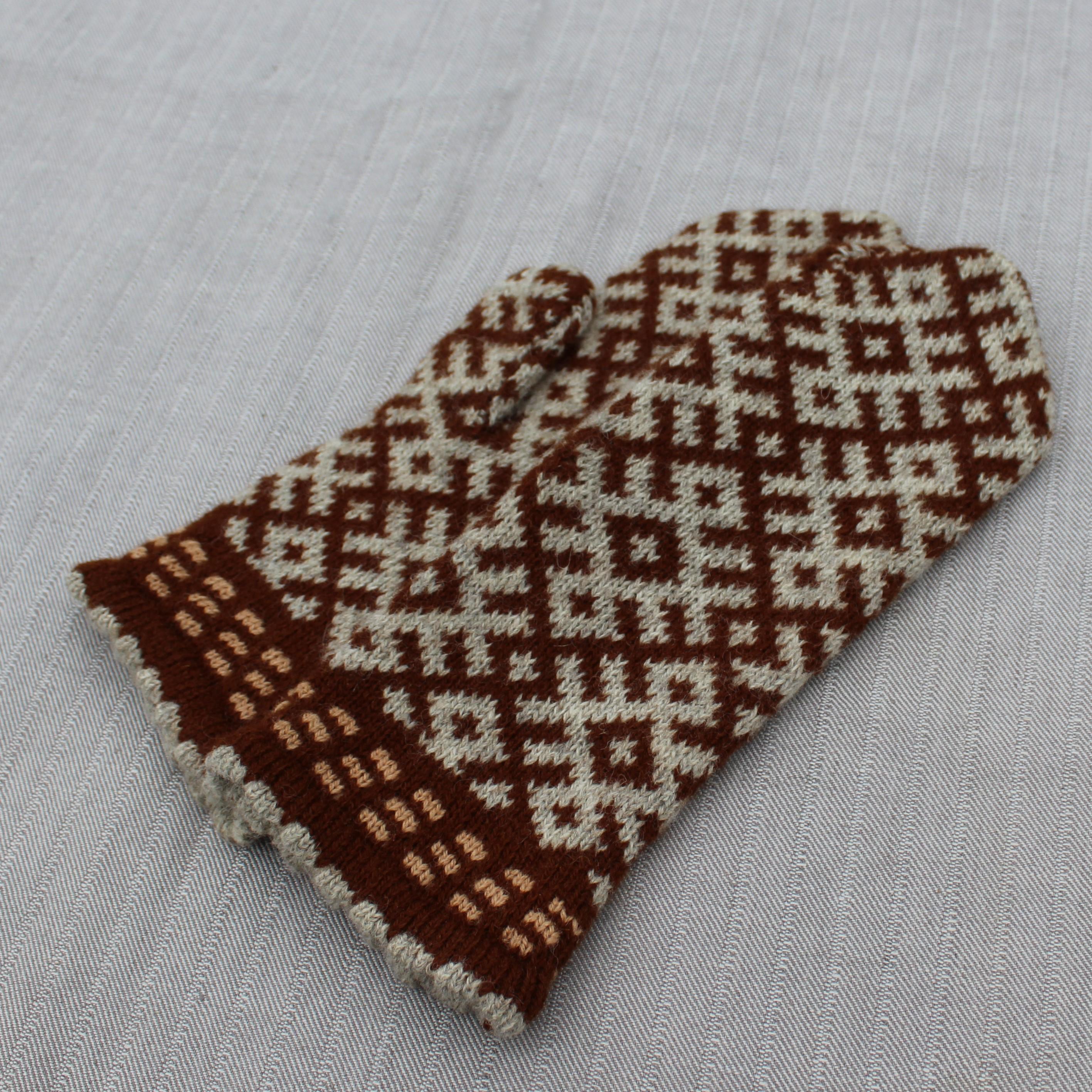 Pair of brown and white patterned mittens on a light gray background