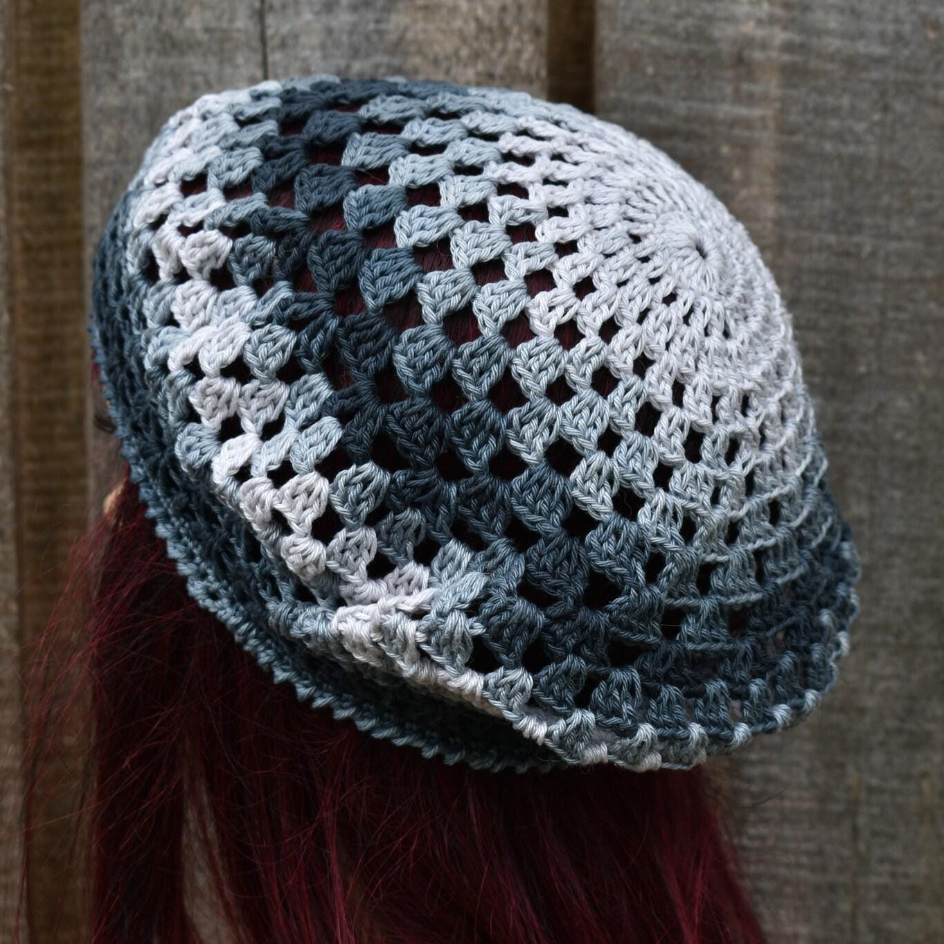 Crocheted beanie with a lattice pattern worn by a person with red hair against a wooden background