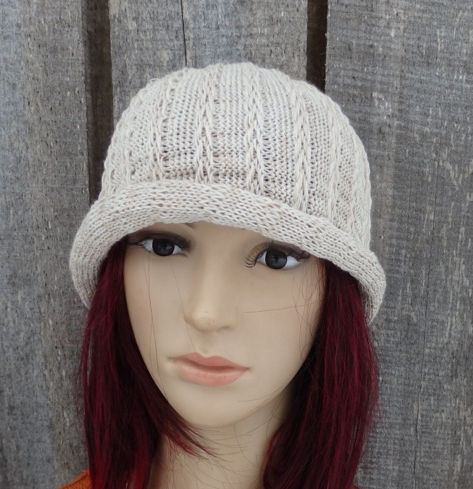 Knitted beige cap on a mannequin head against a wooden background
