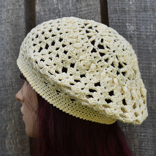 Light yellow crochet hat worn by a person against a wooden background