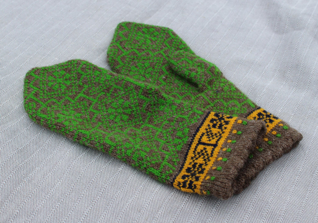 Green and brown knitted mittens with a decorative pattern on a light gray background