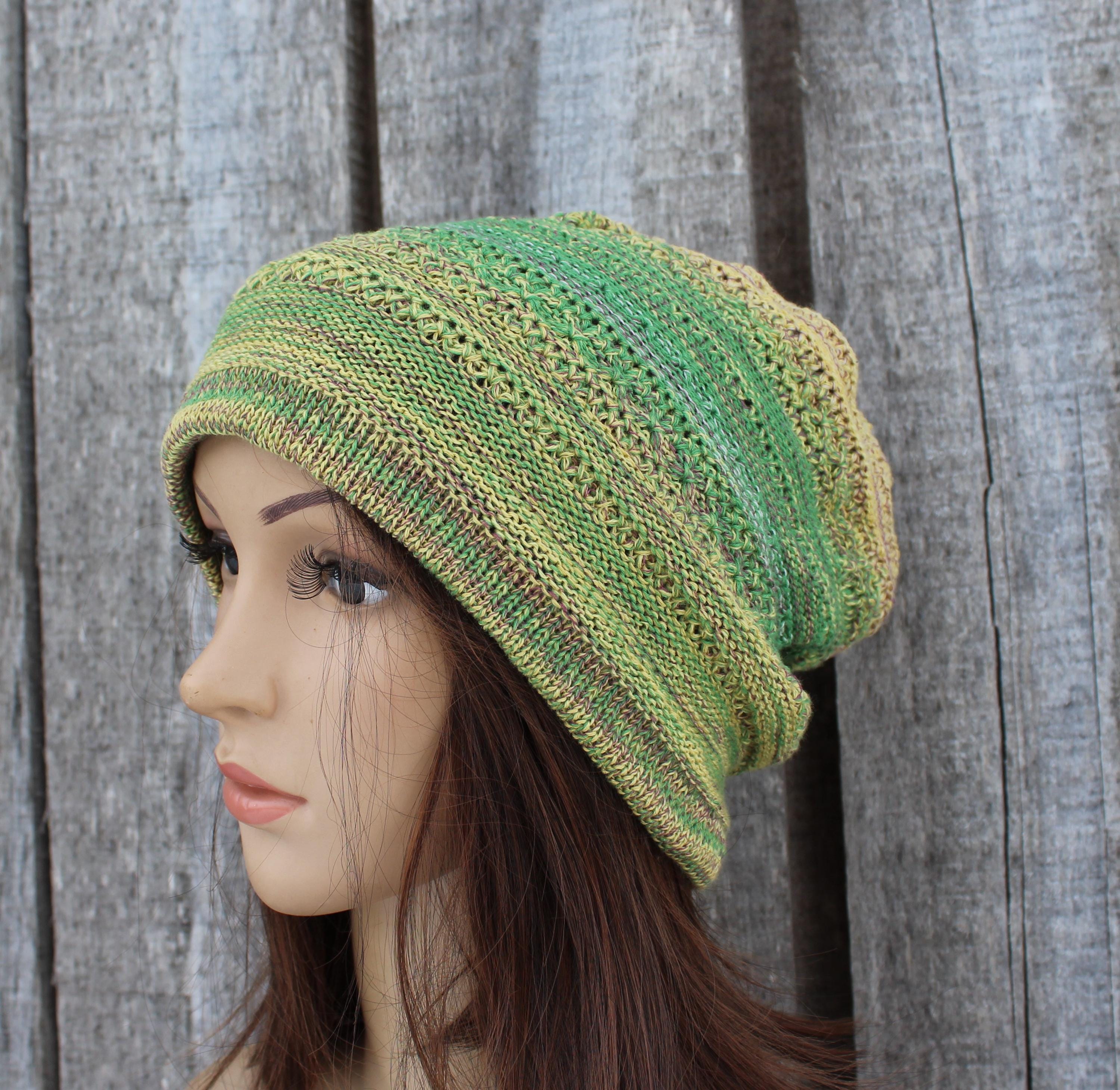 Green knitted beanie on a mannequin head against a wooden background