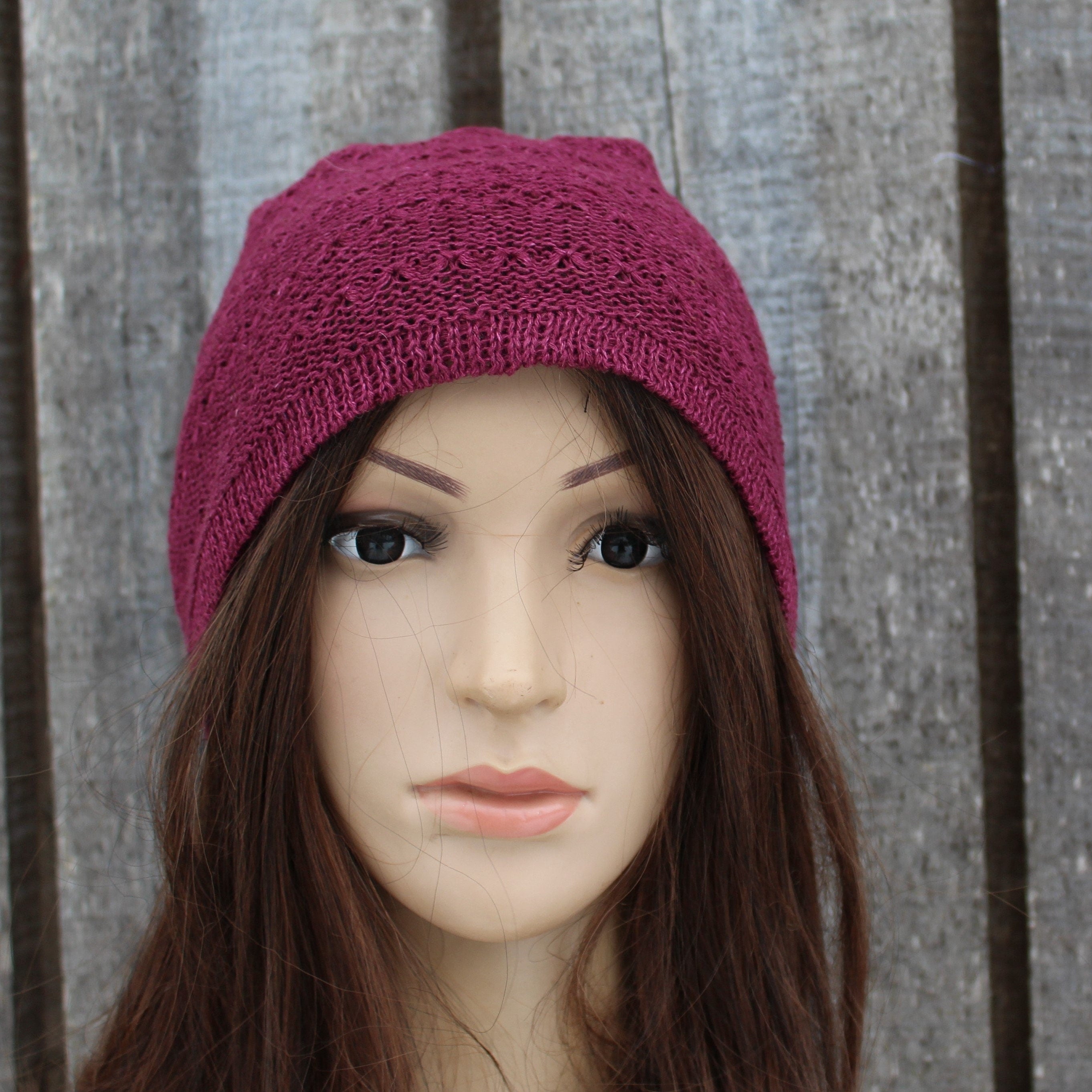 Mannequin head wearing a purple knitted beanie against a wooden background