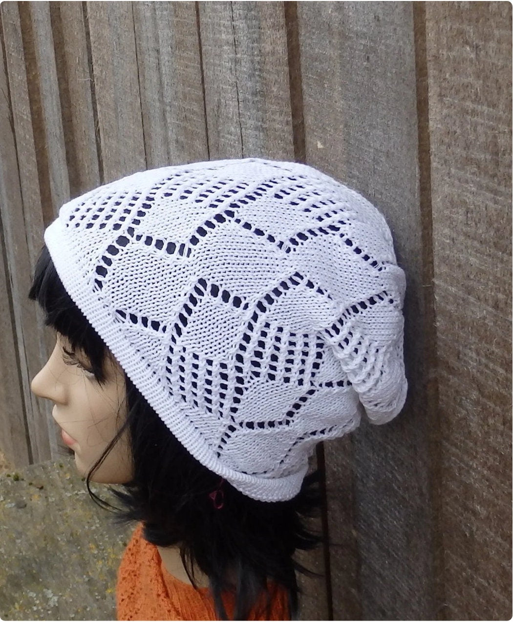 Person wearing a white knitted headscarf against a wooden background