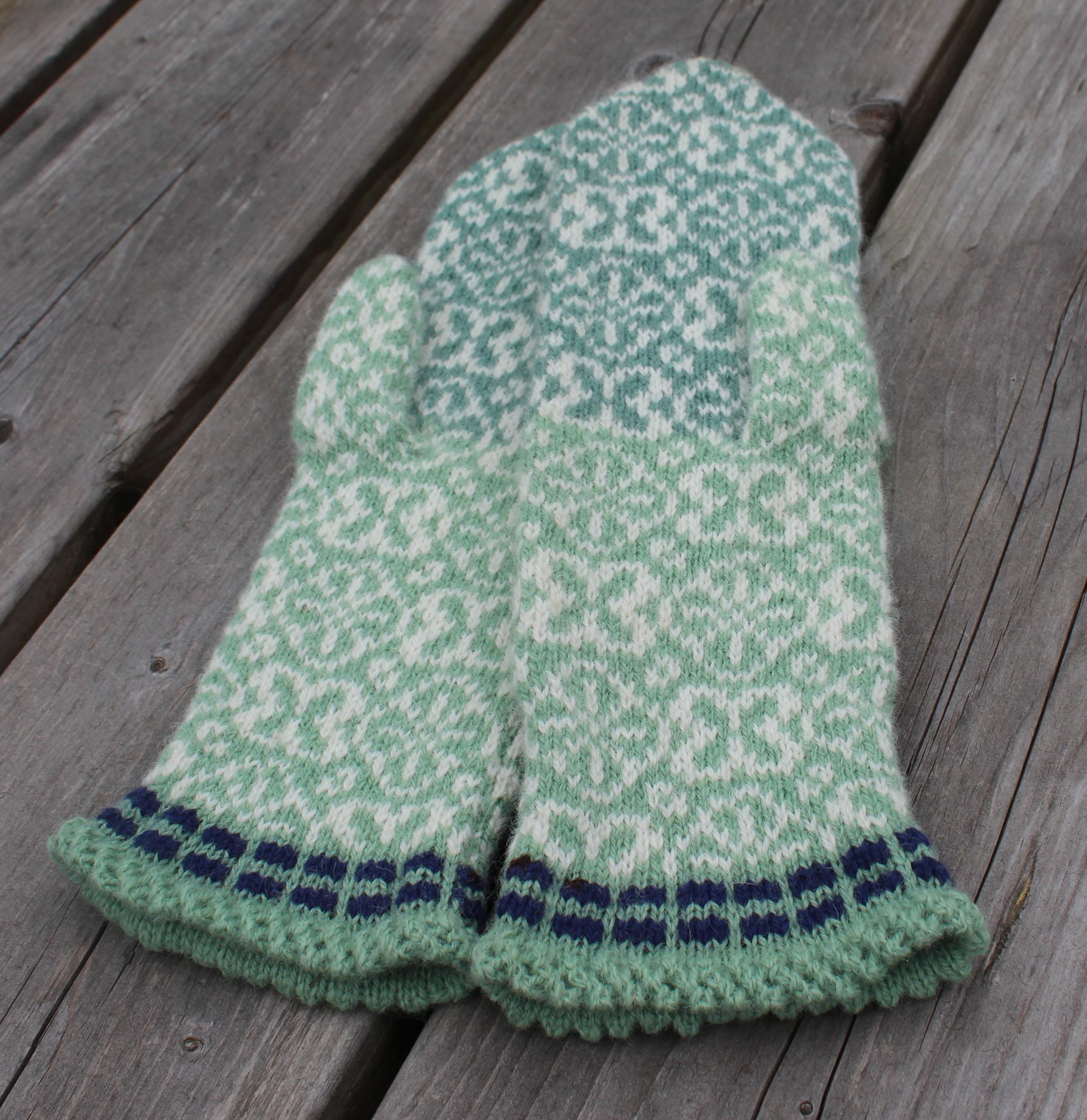 Green and white patterned knitted gloves on a wooden surface