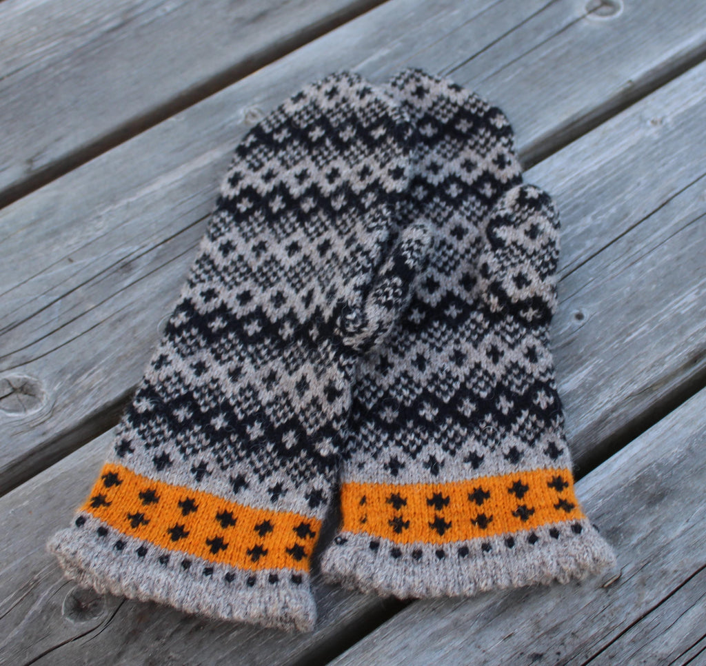 Pair of knitted mittens with a geometric pattern on a wooden surface