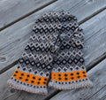 Pair of knitted mittens with a geometric pattern on a wooden surface