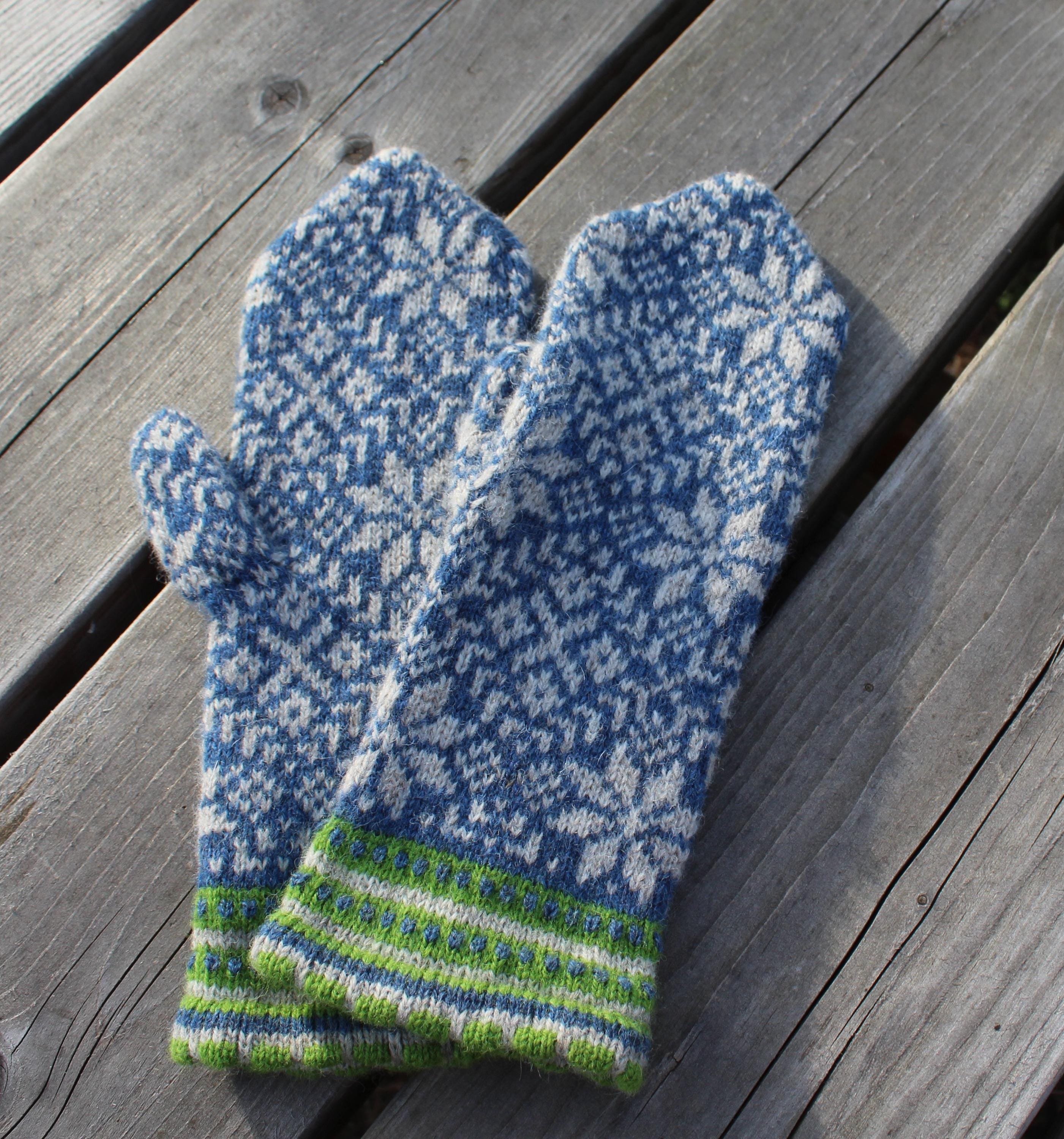 Pair of blue and white patterned mittens on a wooden surface