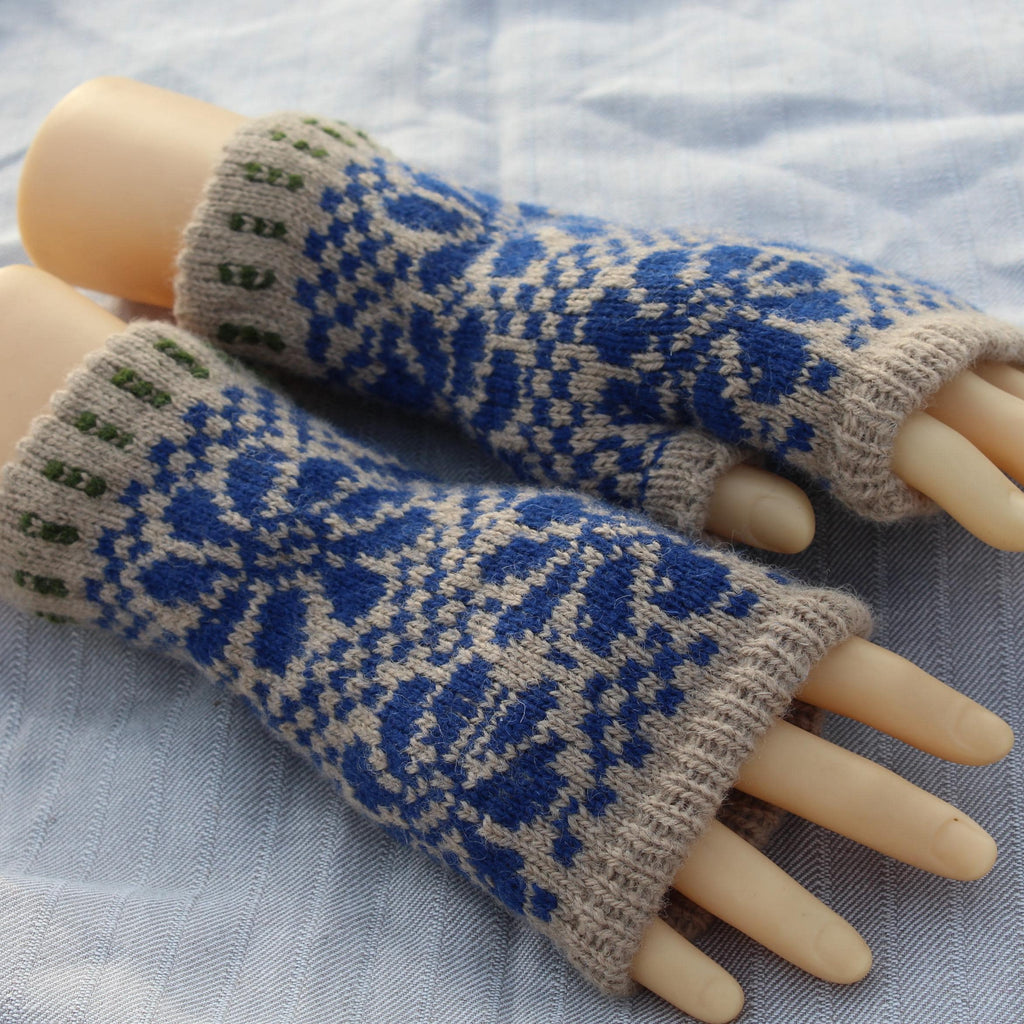 Pair of blue and beige patterned fingerless gloves on a mannequin hand against a light fabric background.