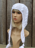 White knitted bonnet on a mannequin head against a wooden background
