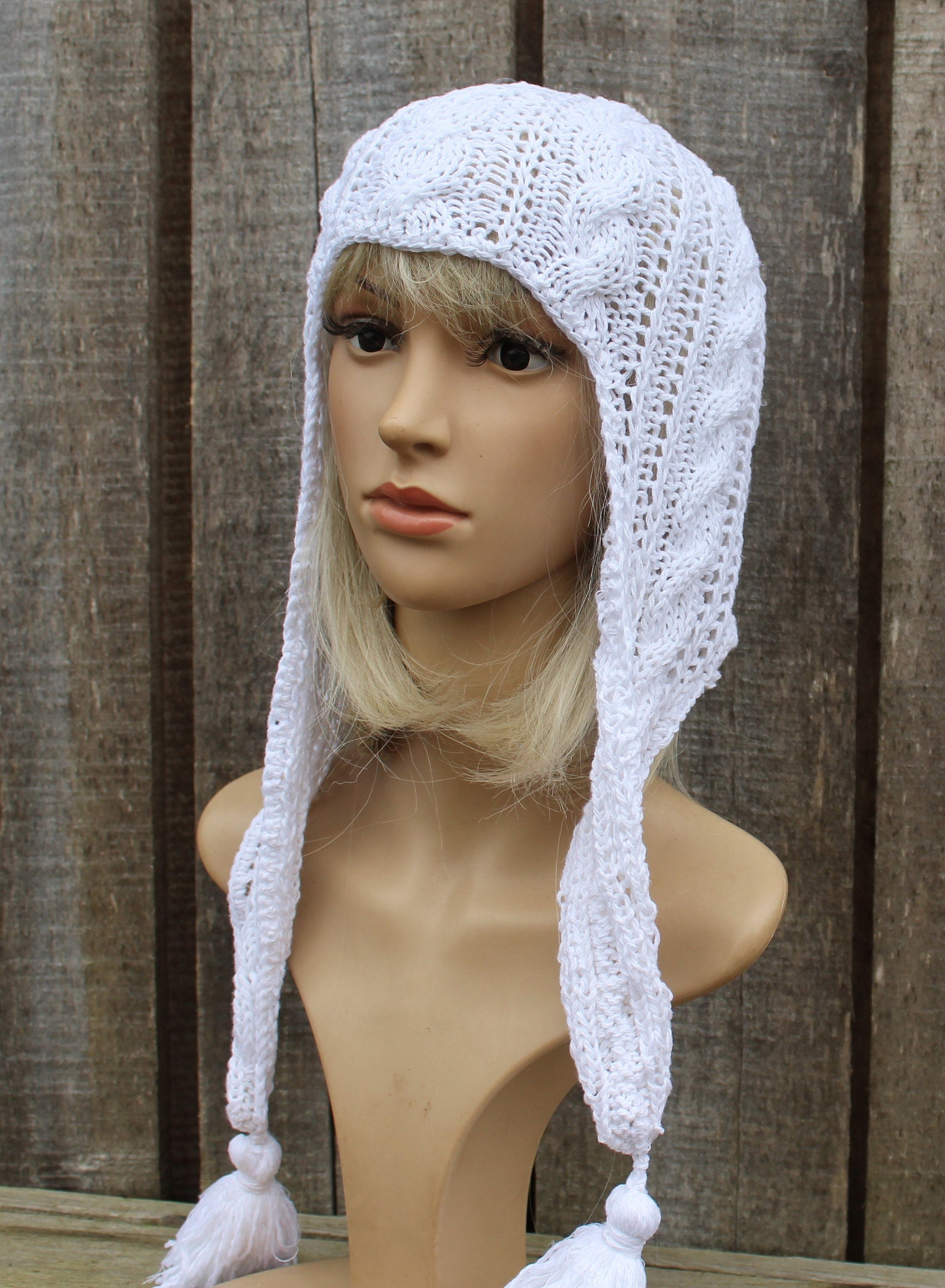 White knitted bonnet on a mannequin head against a wooden background