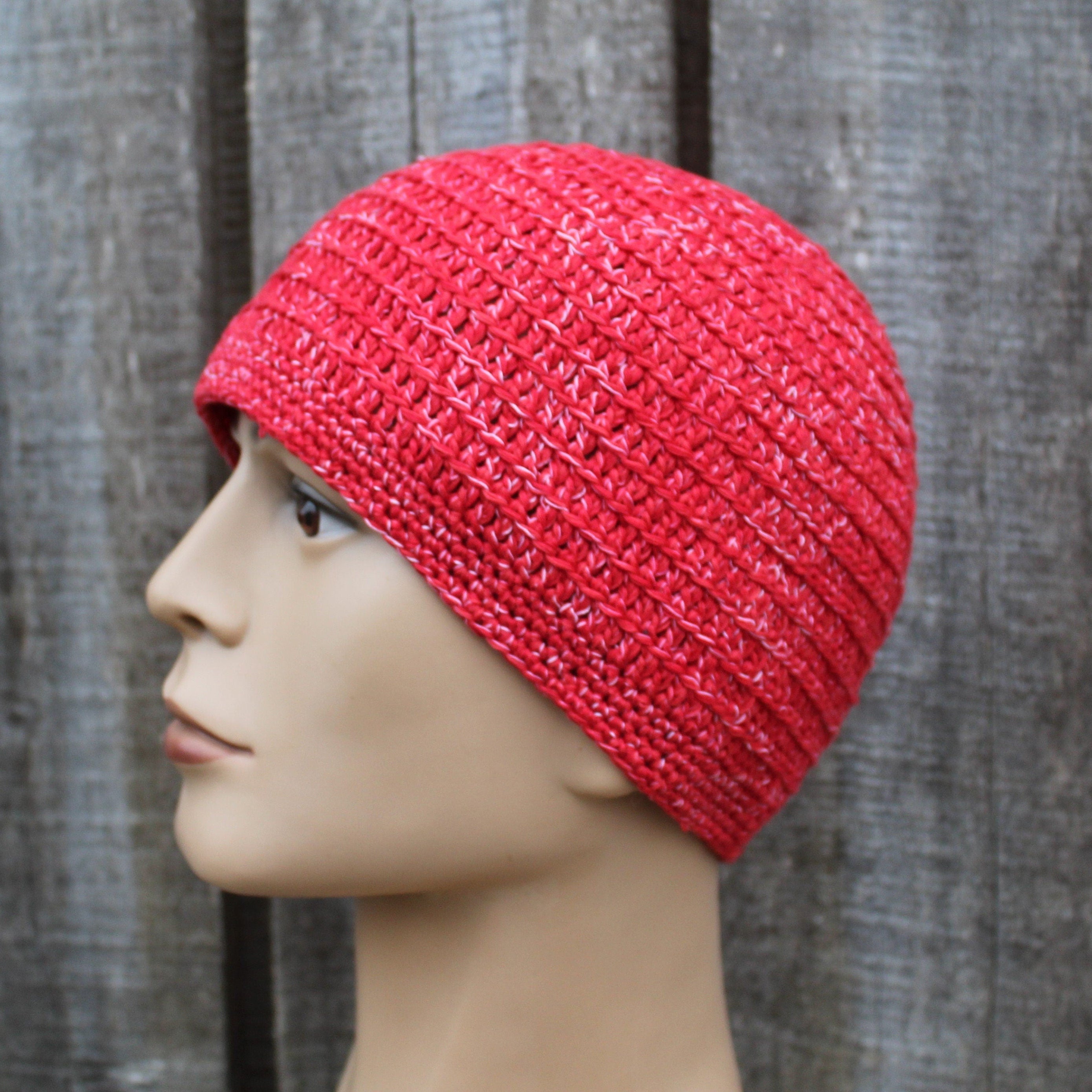 Red knitted beanie on a mannequin head against a wooden background