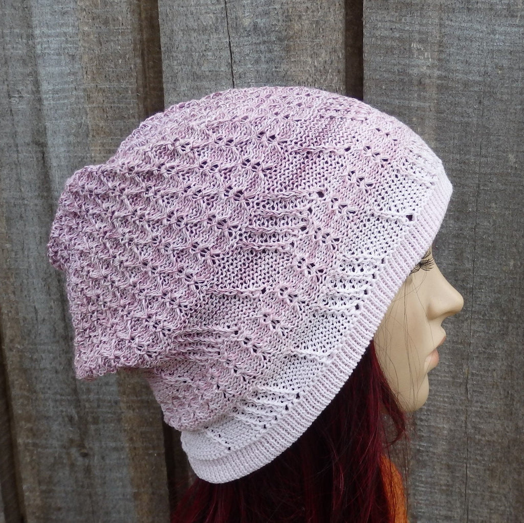 Knitted pink beanie on a mannequin head against a wooden background