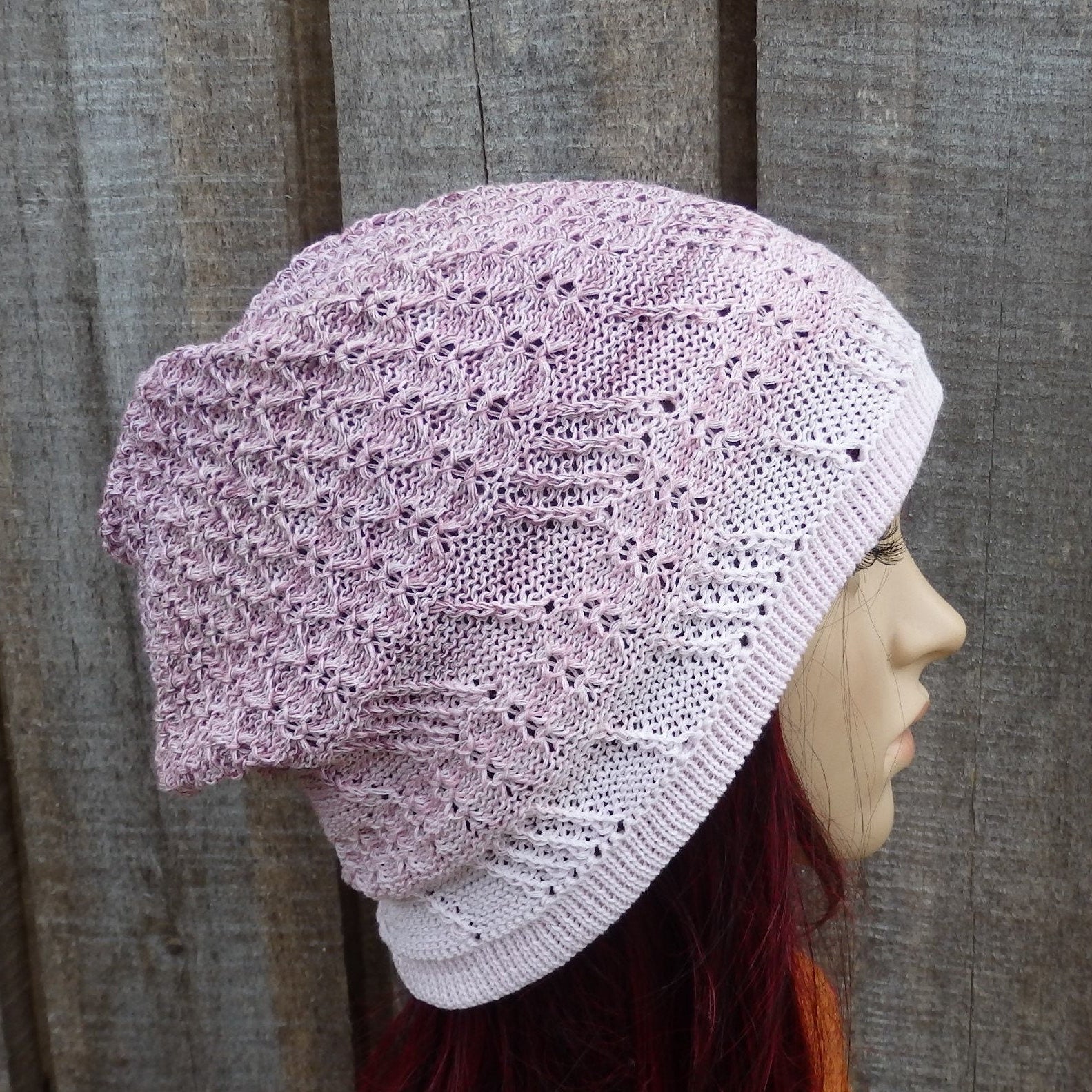 Knitted pink beanie on a mannequin head against a wooden background