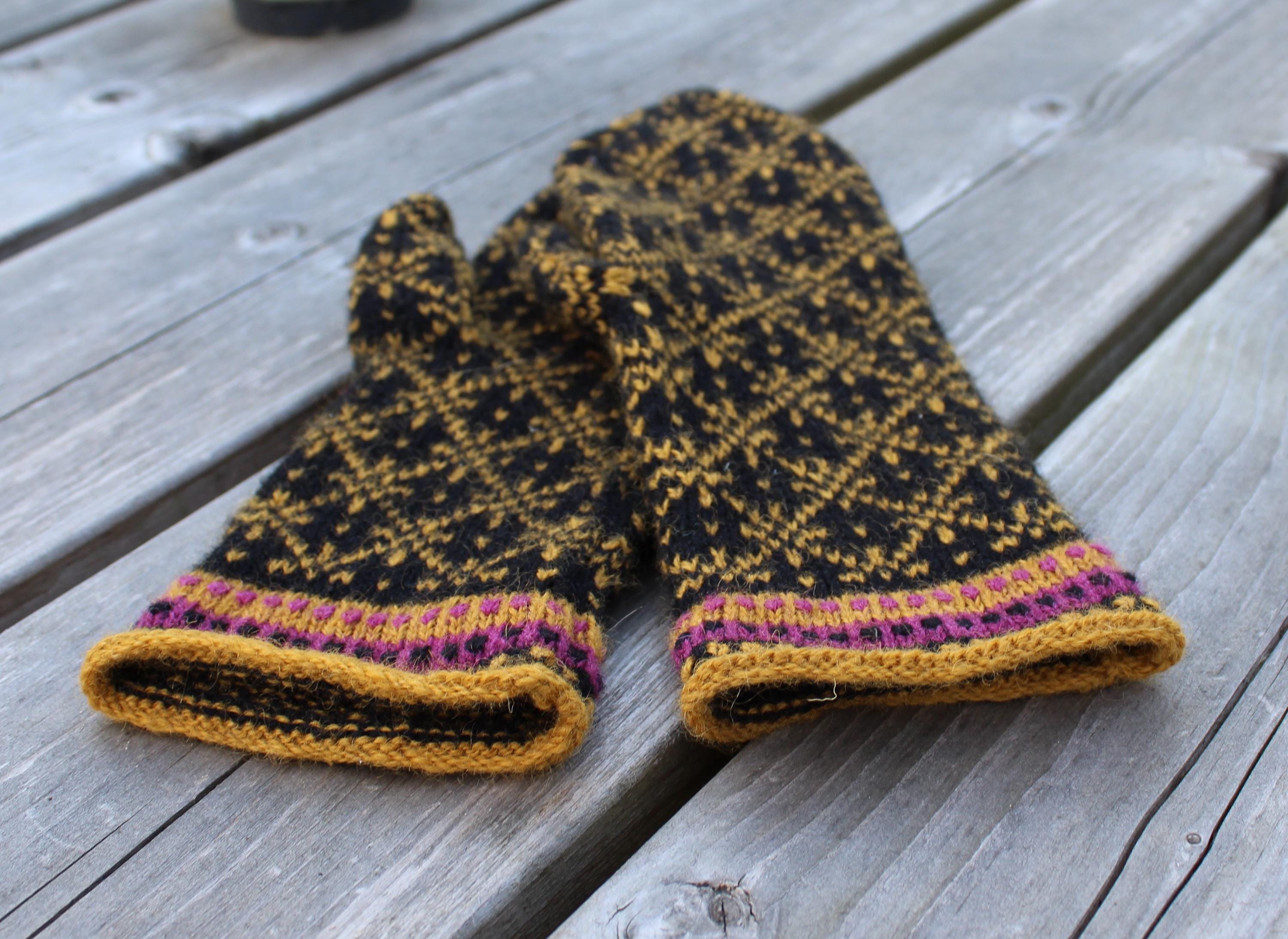 Pair of black and gold knitted mittens on a wooden surface