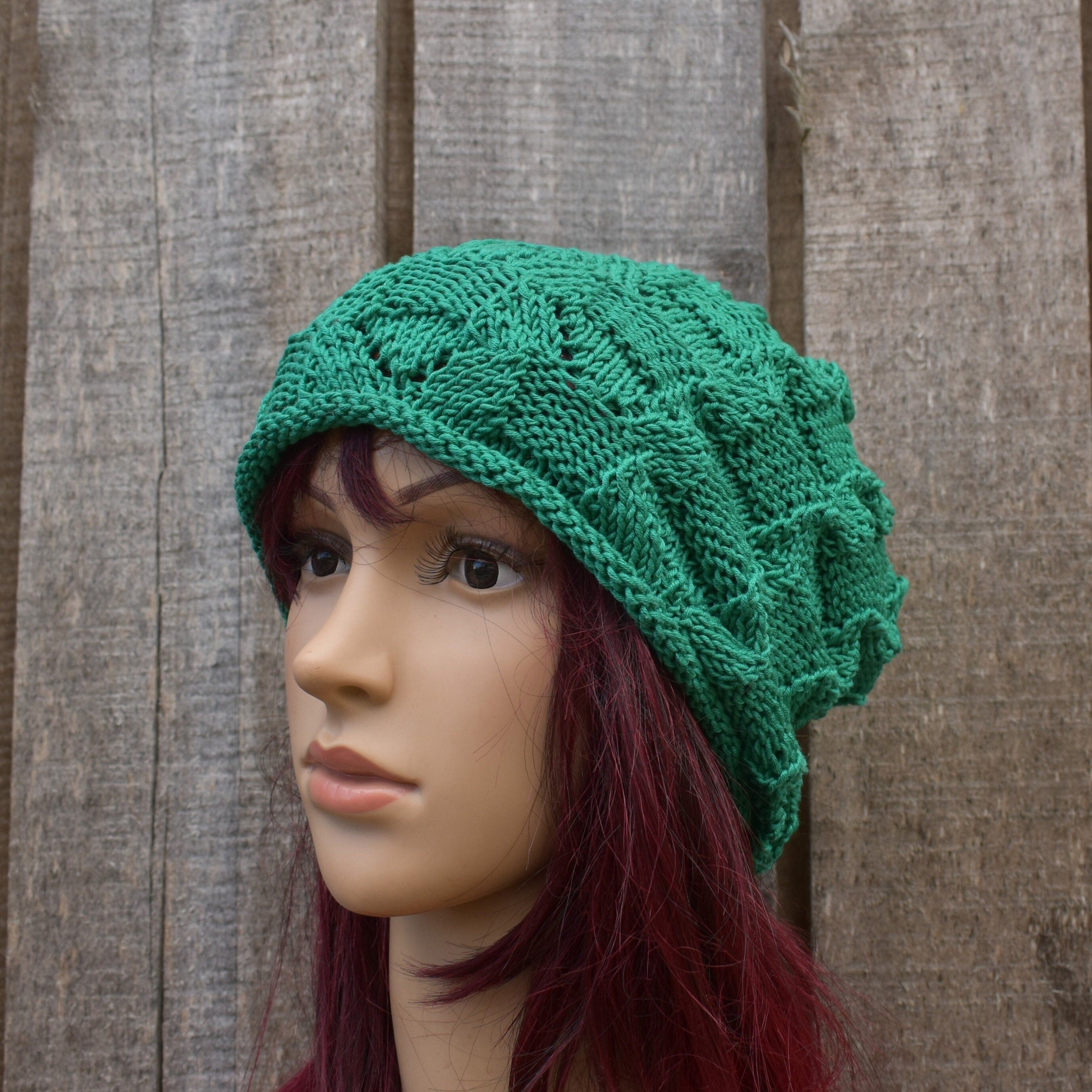 Green knitted hat on a mannequin head against a wooden background
