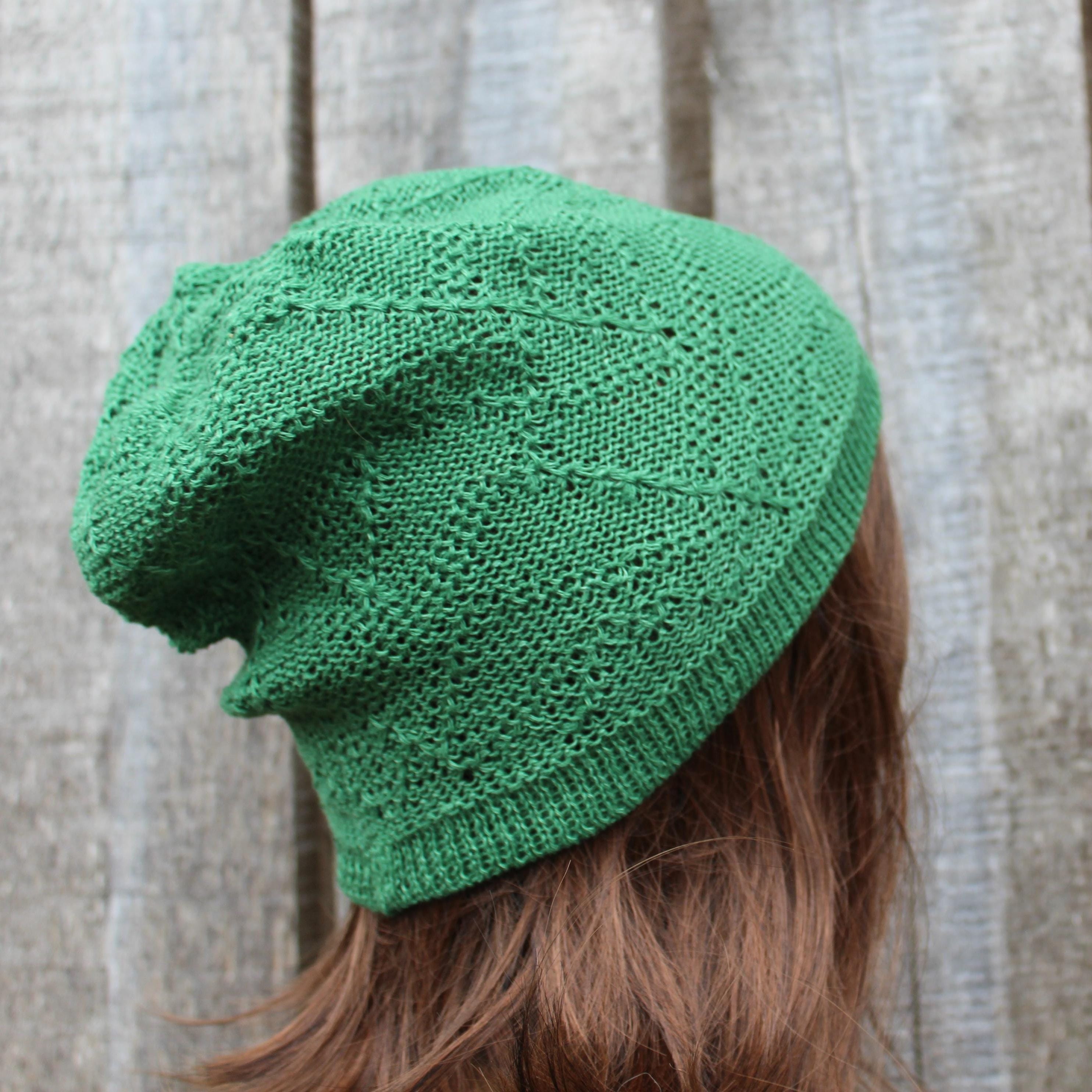 Green knitted beanie worn by a person with brown hair against a neutral background