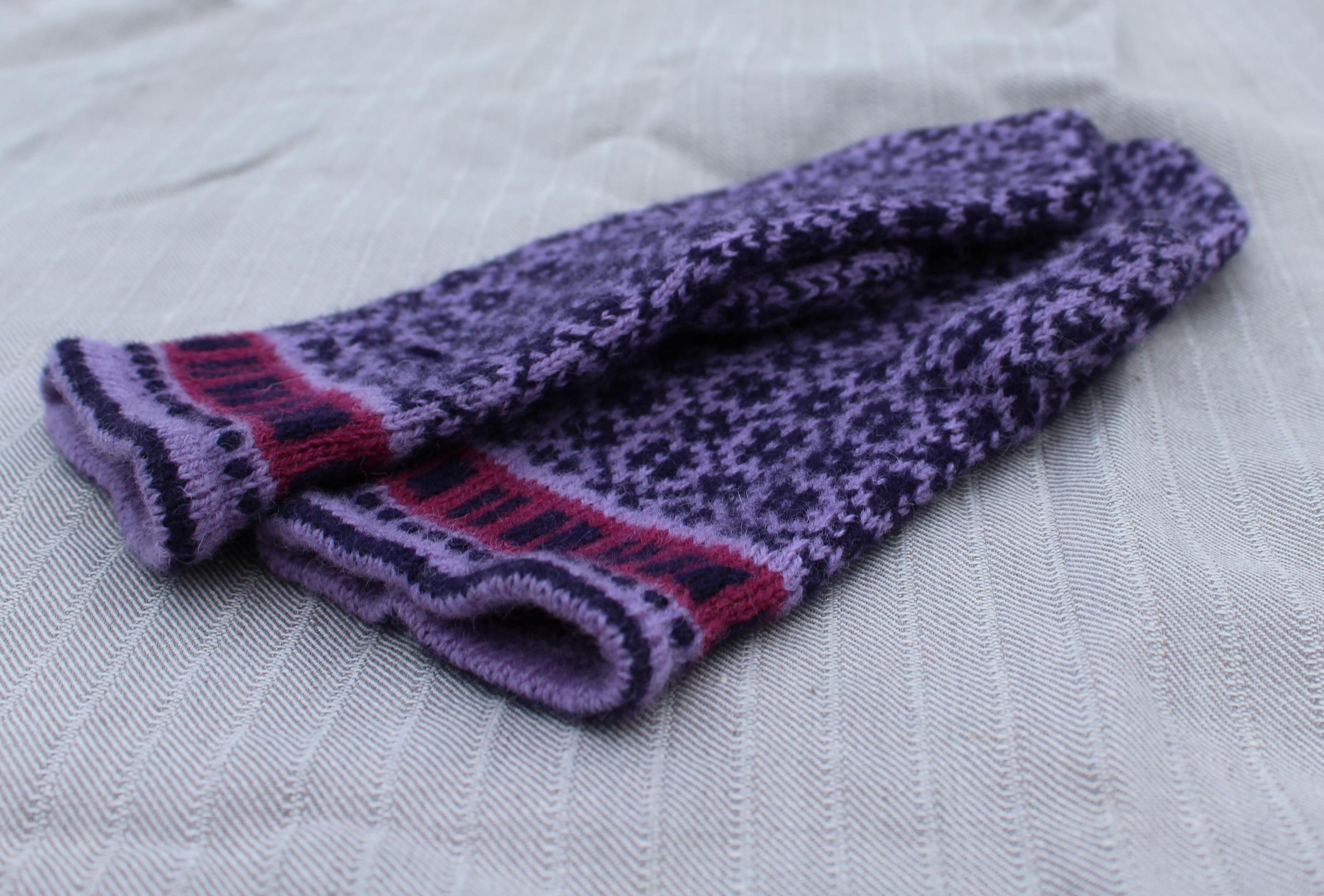 Pair of purple and pink patterned socks on a textured white background