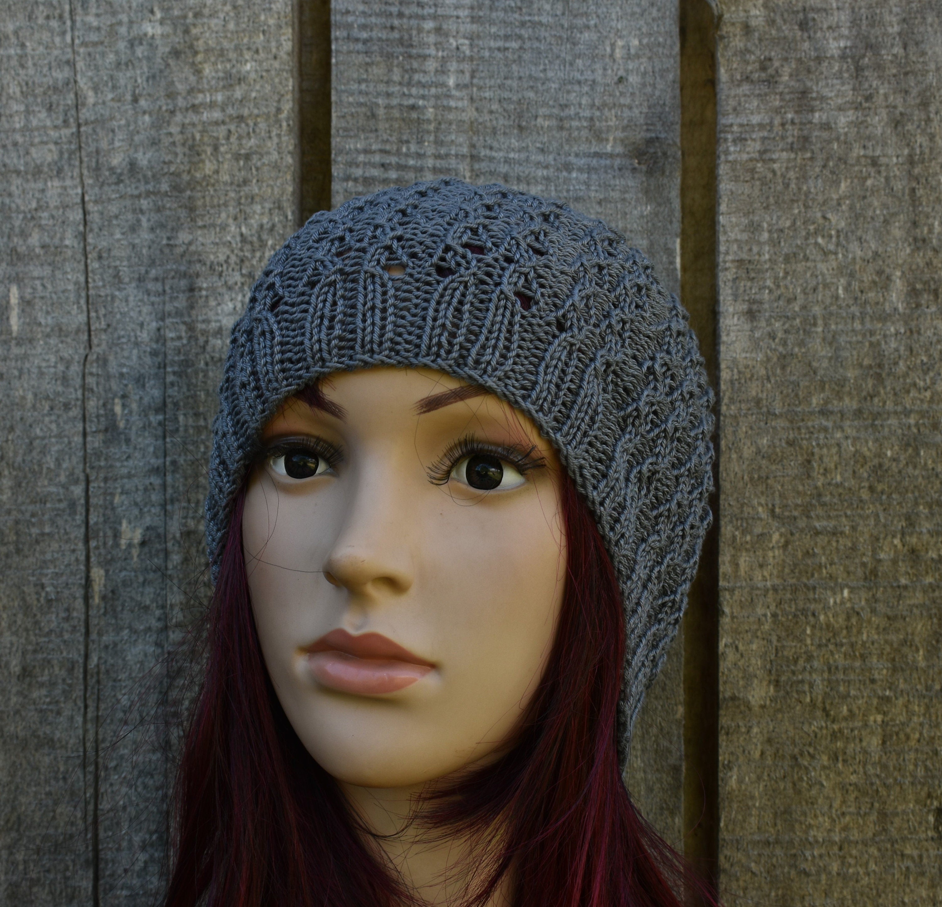 Mannequin head wearing a gray knit beanie against a wooden background