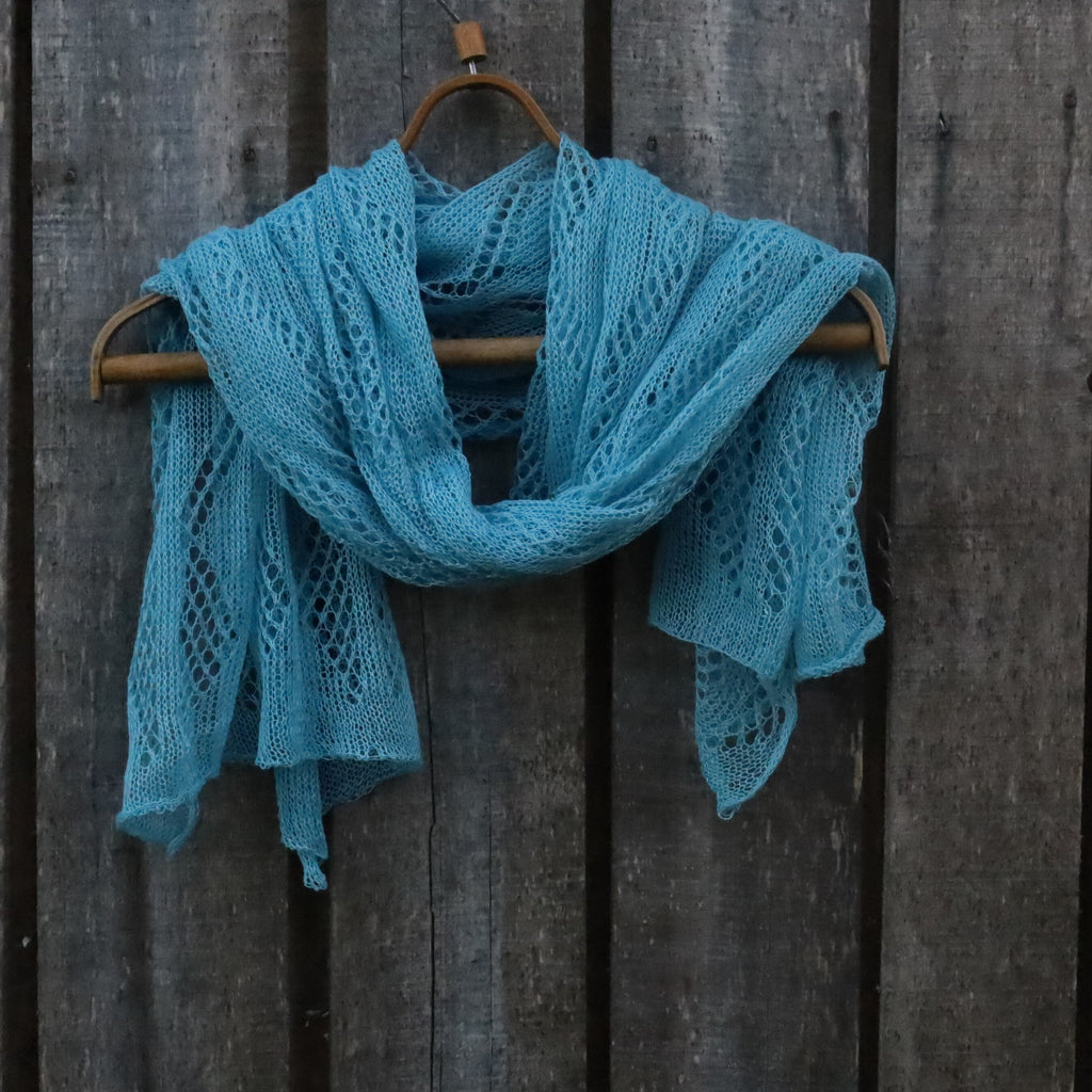 Blue knitted scarf on a wooden hanger against a wooden background