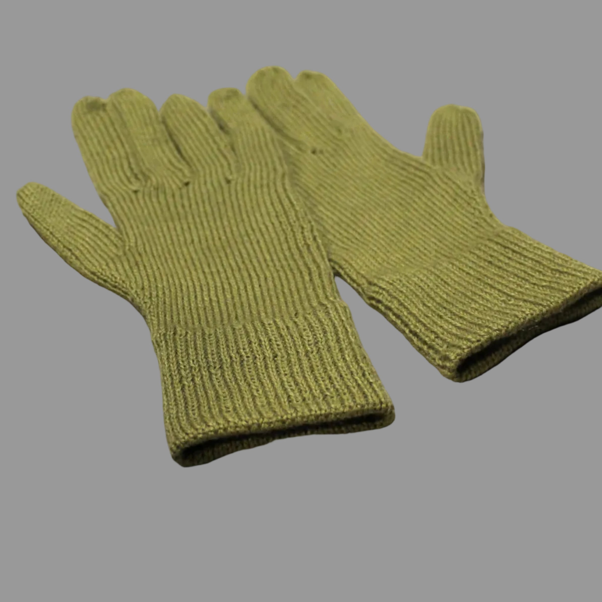 Pair of green knitted gloves on a textured beige surface