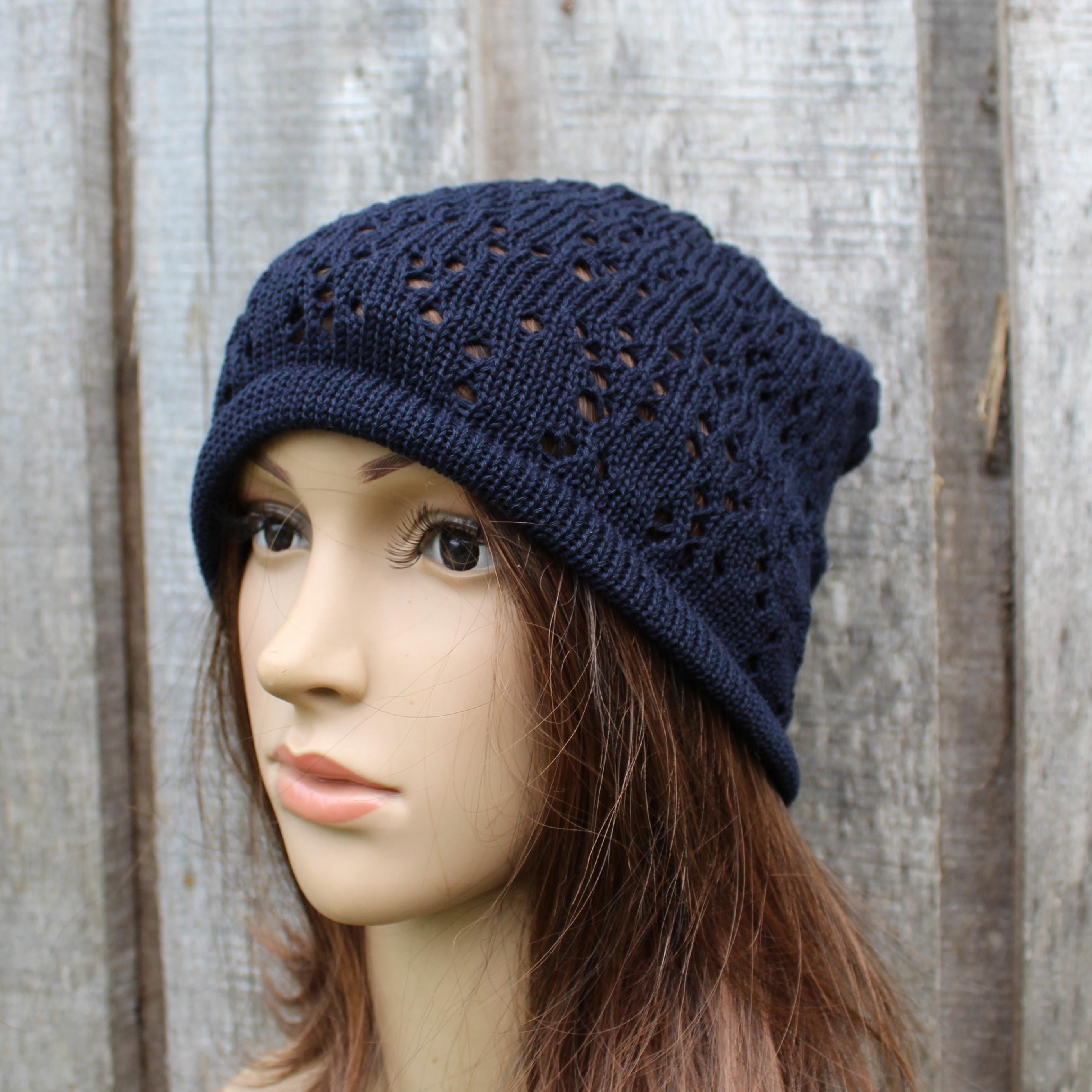 Navy blue knitted hat on a mannequin head against a wooden background
