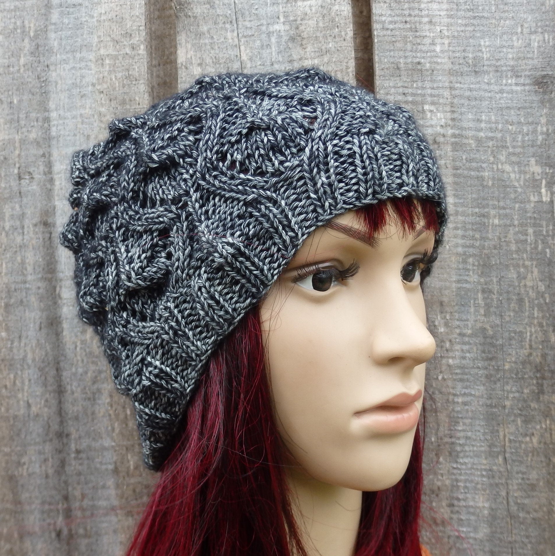 Knitted gray beanie on a mannequin head against a wooden background