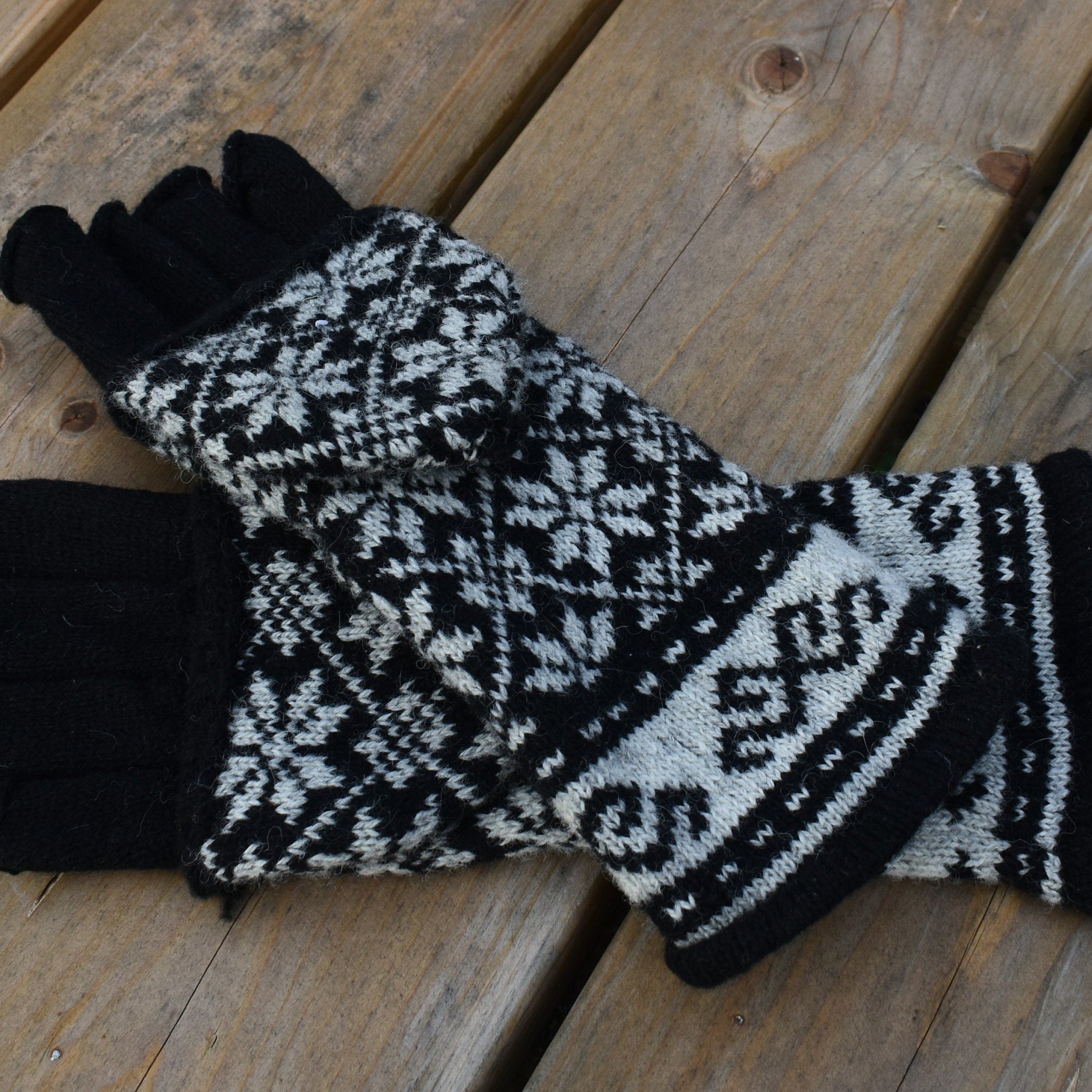 Pair of black and white patterned gloves on a wooden surface