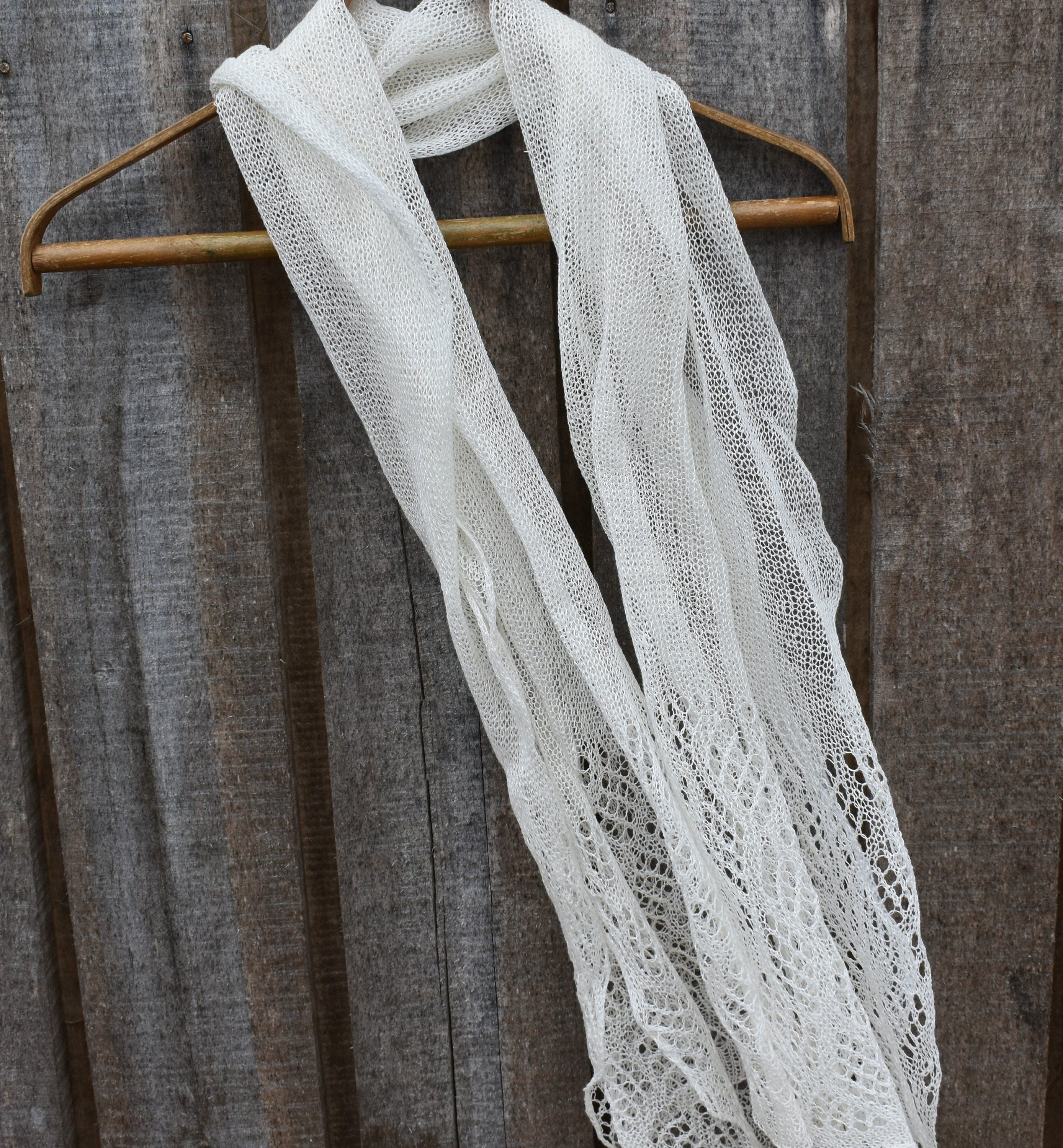 White lace scarf on a wooden hanger against a rustic wooden background