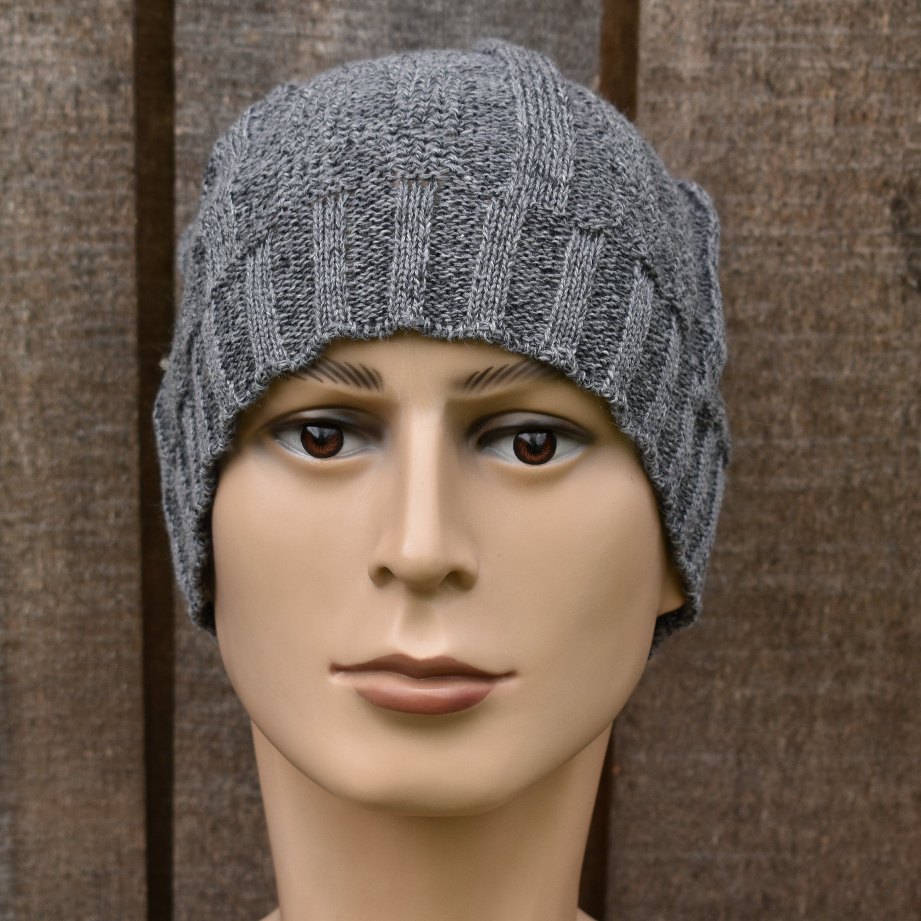 Gray knit beanie on a mannequin head against a brown background