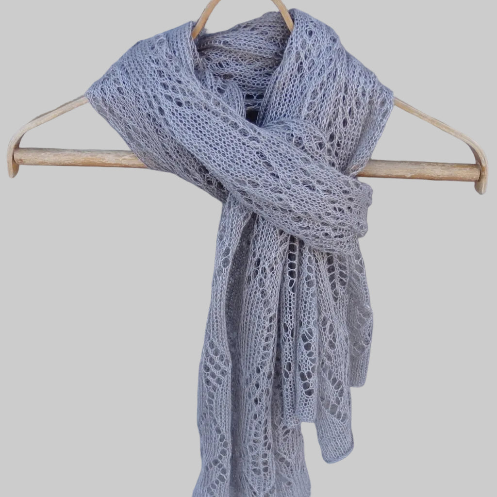 Gray knitted scarf on a wooden hanger against a textured gray background