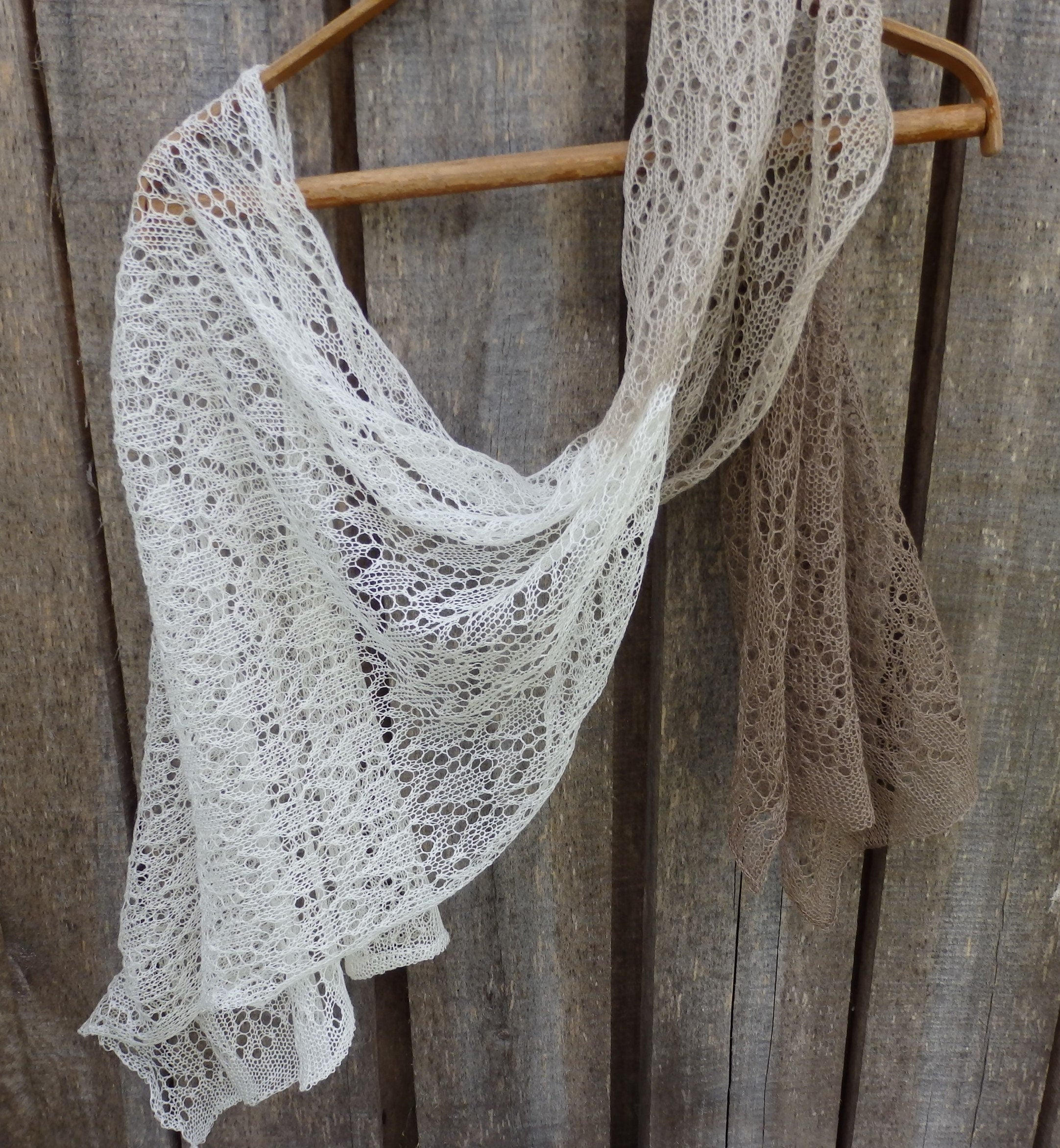 Lace shawl draped over a wooden hanger against a rustic wooden background