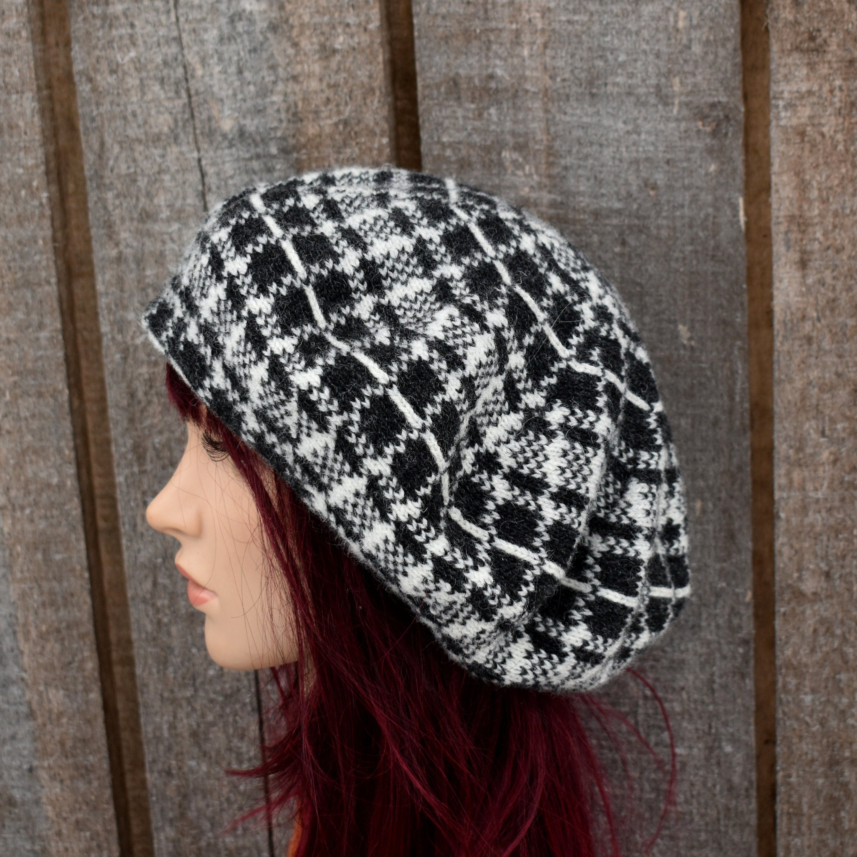 Black and white checkered knitted hat on a mannequin head against a wooden panel background
