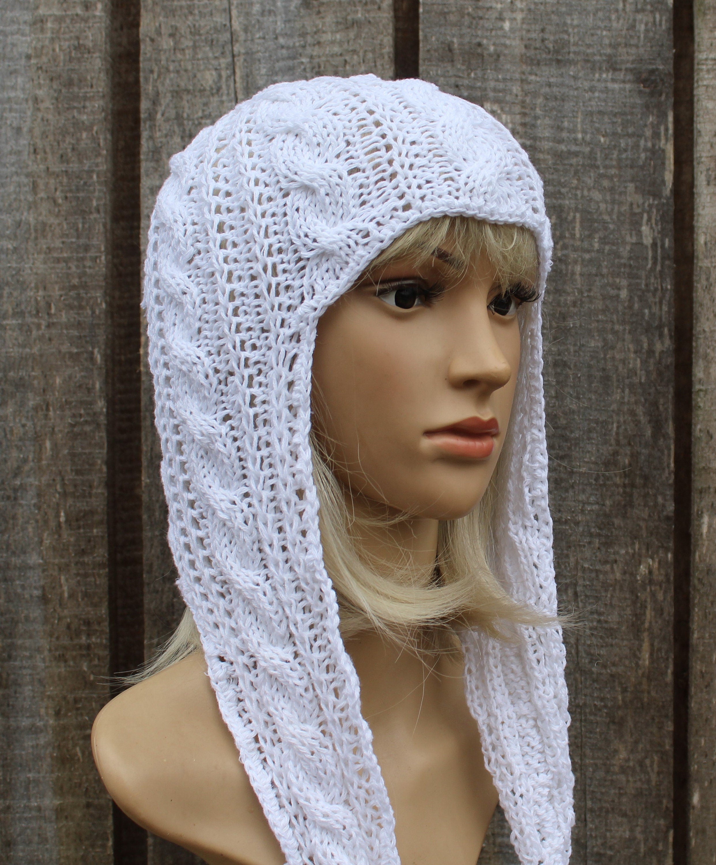 White knitted hood on a mannequin against a wooden background