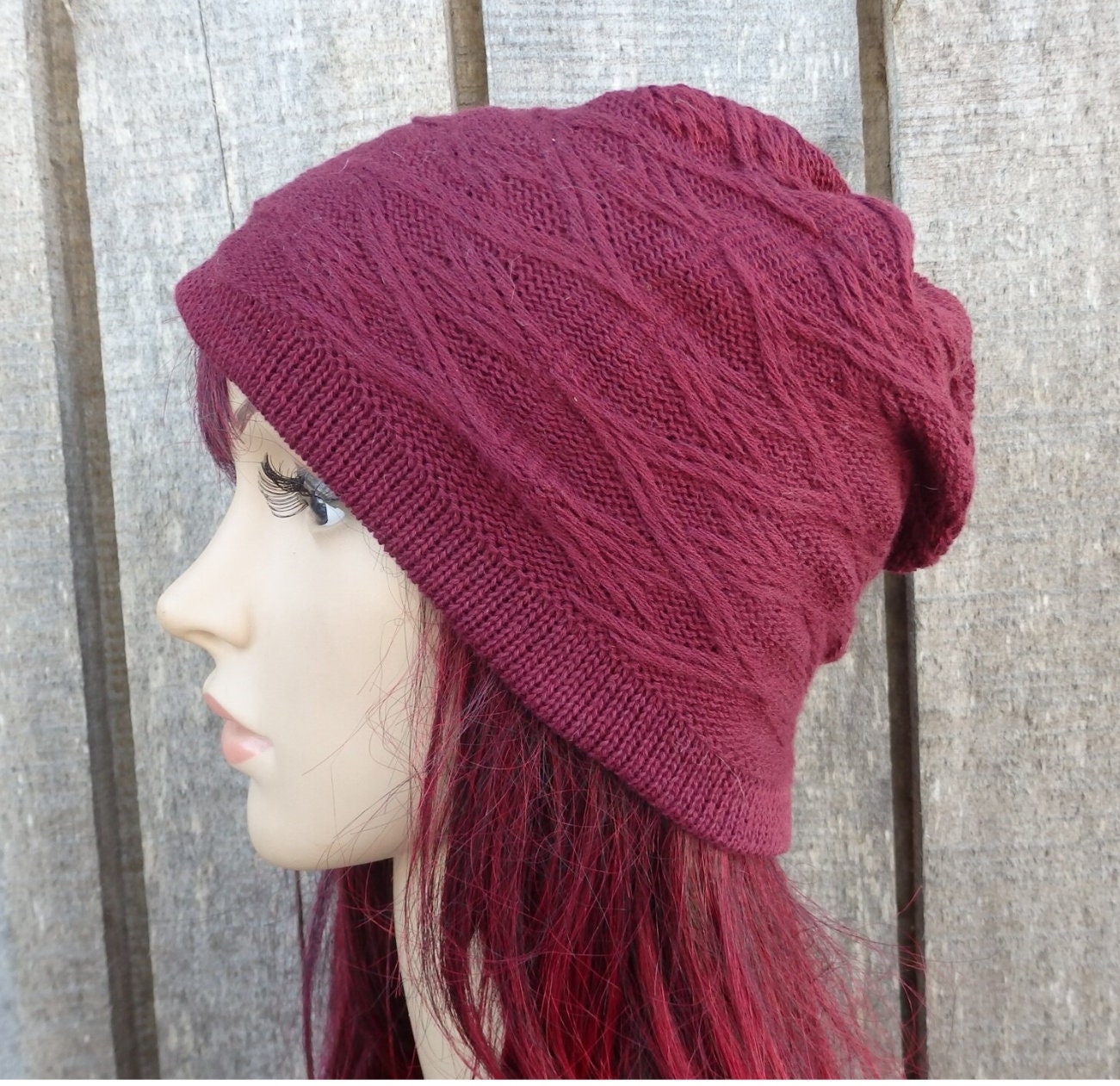 Maroon knitted beanie on a mannequin head against a wooden background