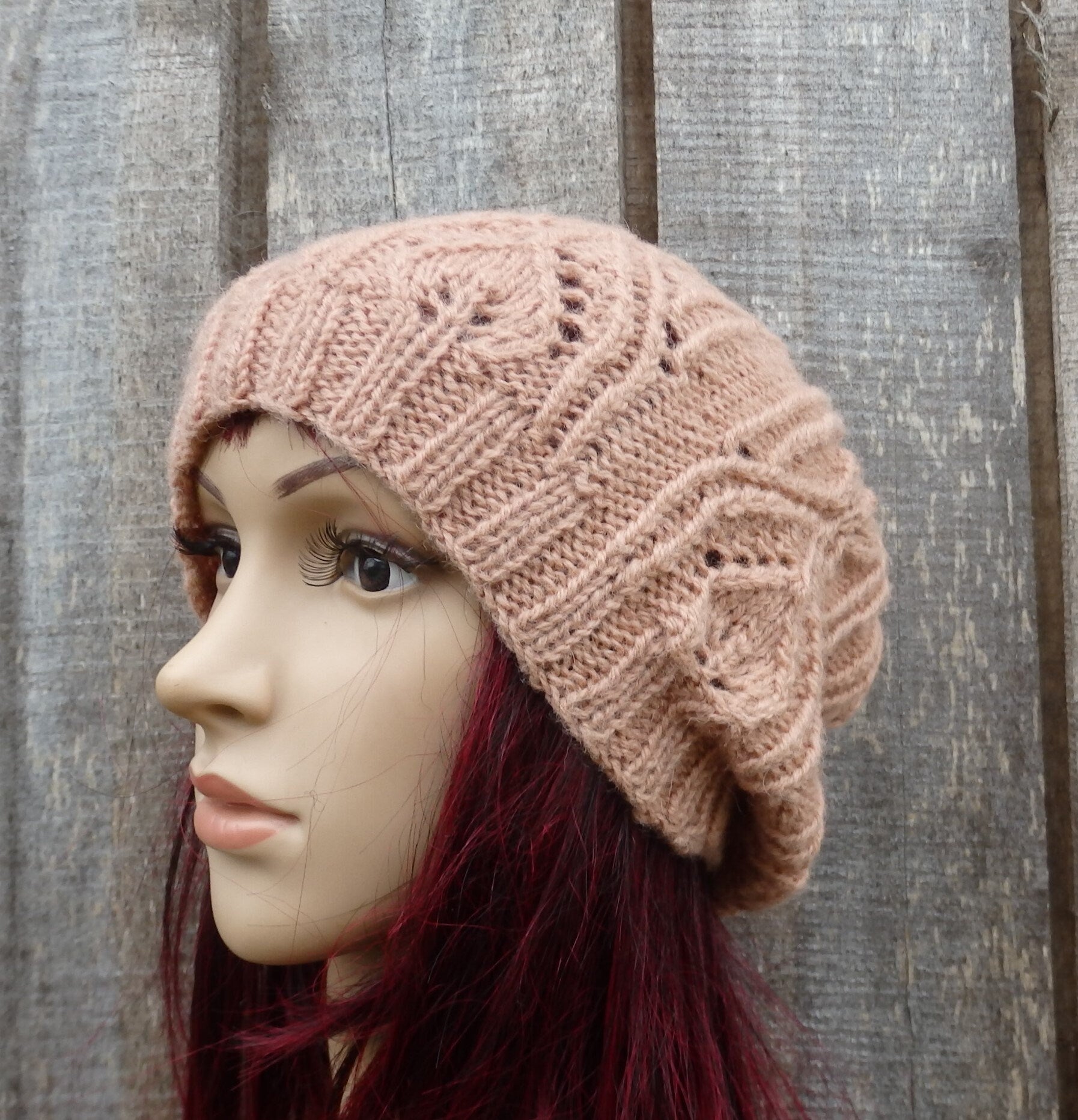 Knitted beige beanie on a mannequin head against a wooden background