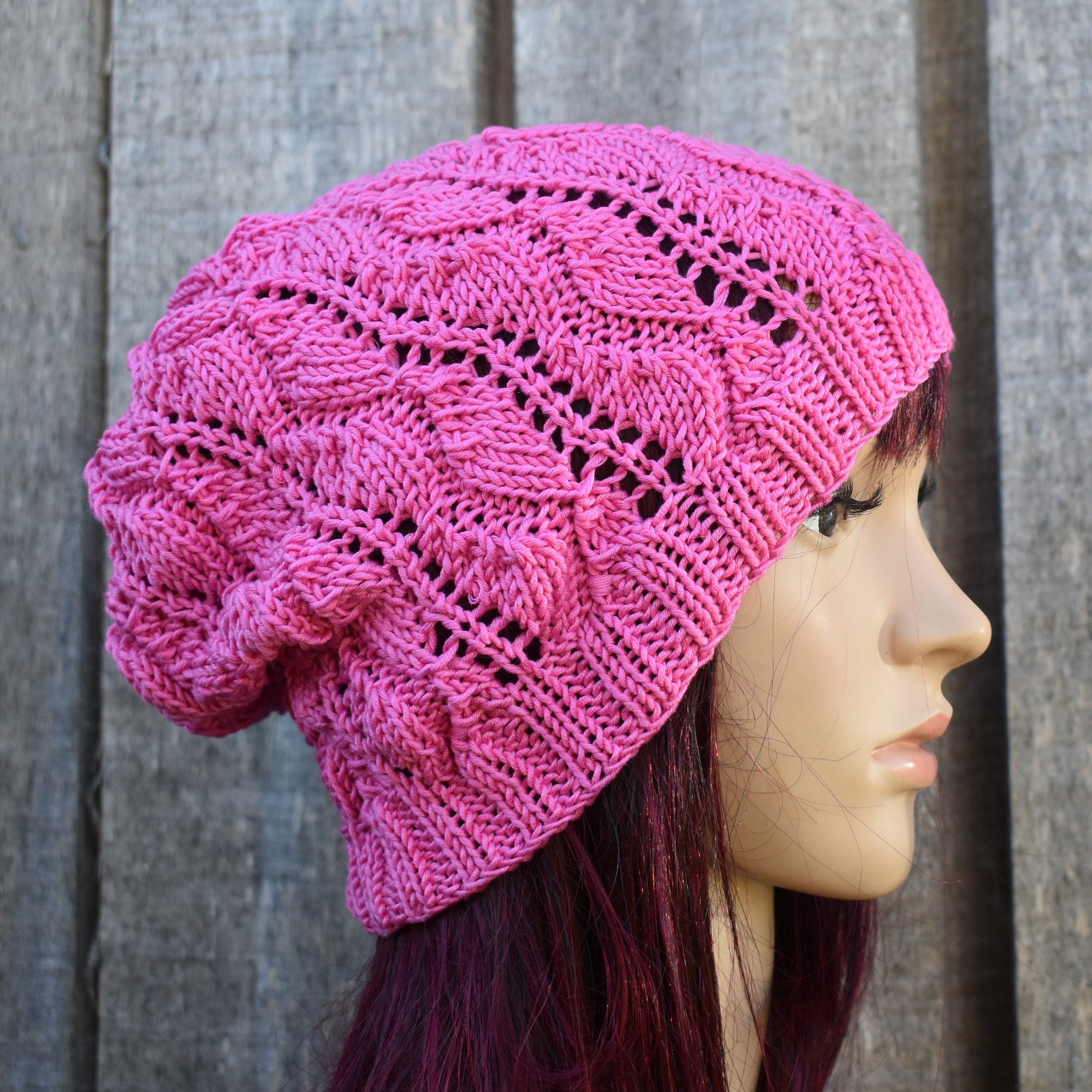 Pink knitted beanie on a mannequin head against a wooden background