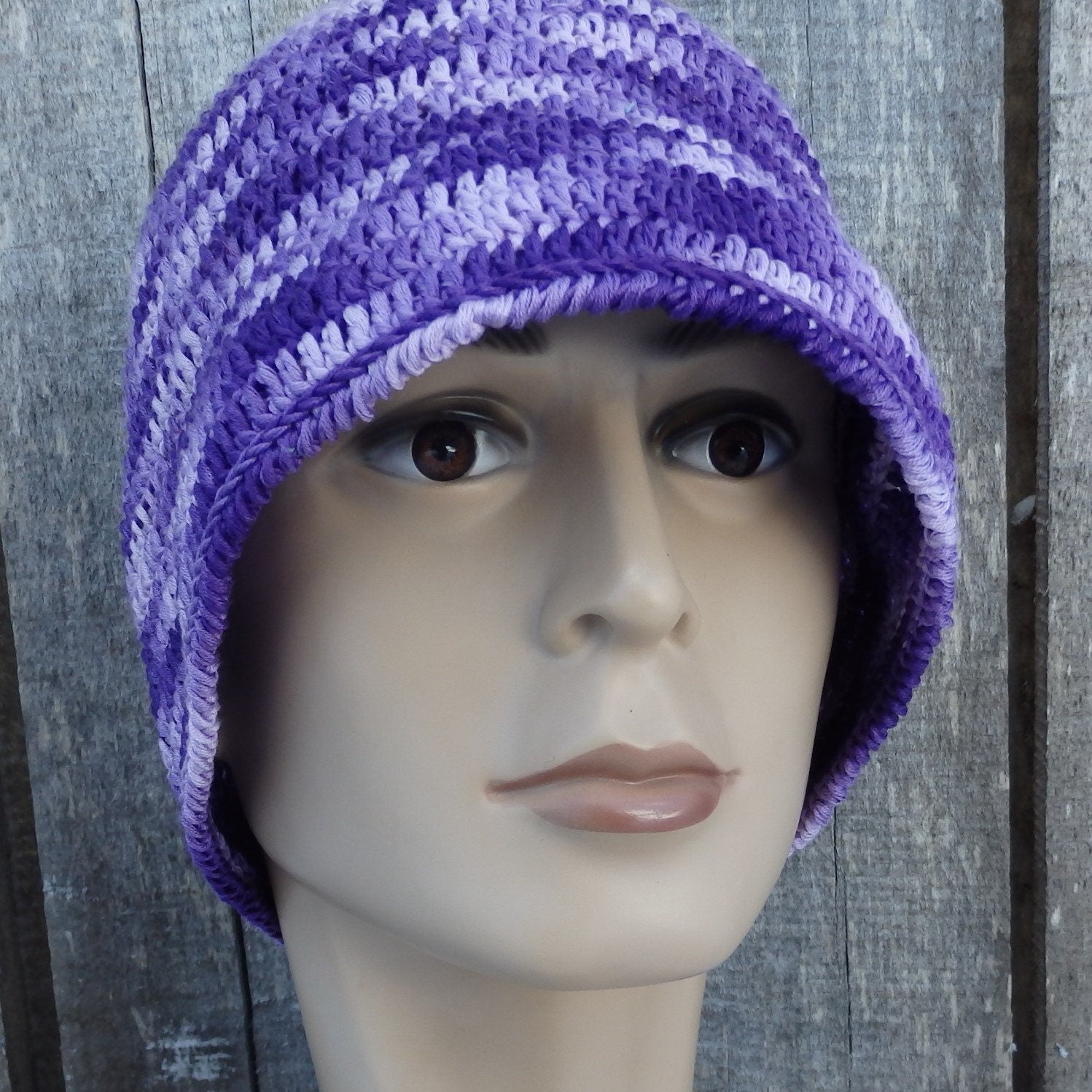 Purple knitted hat on a mannequin head against a wooden background