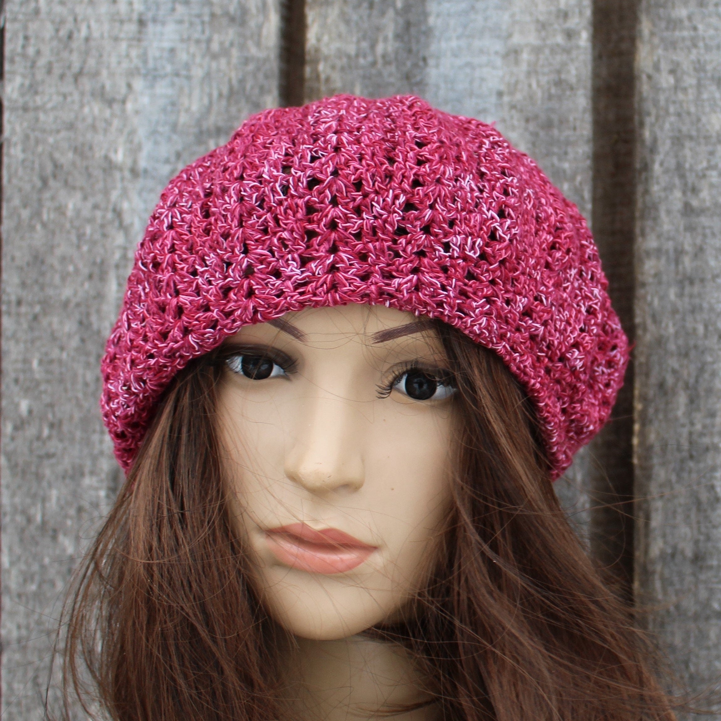 Pink knitted hat on a mannequin head against a wooden panel background