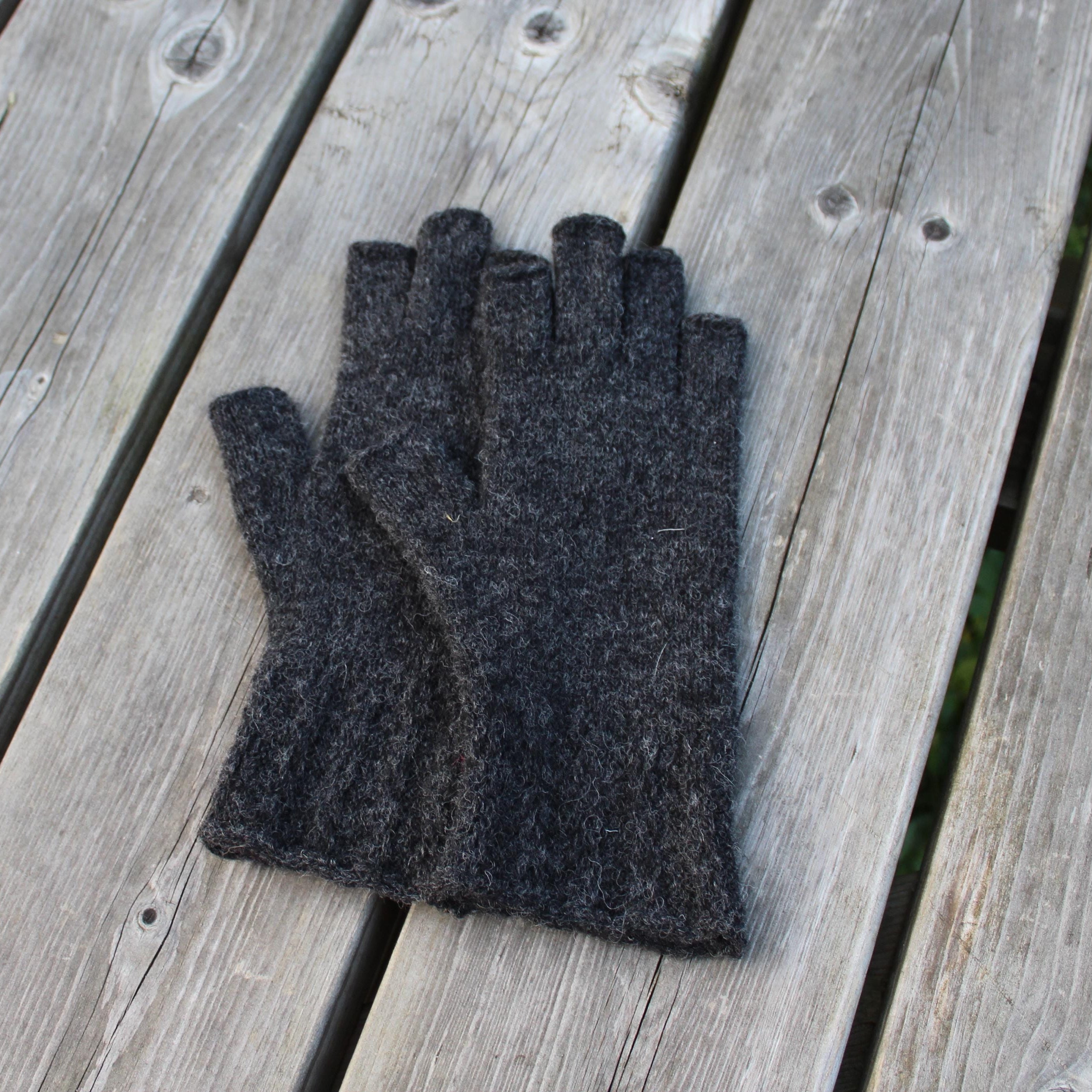 Pair of dark gray gloves on a wooden surface