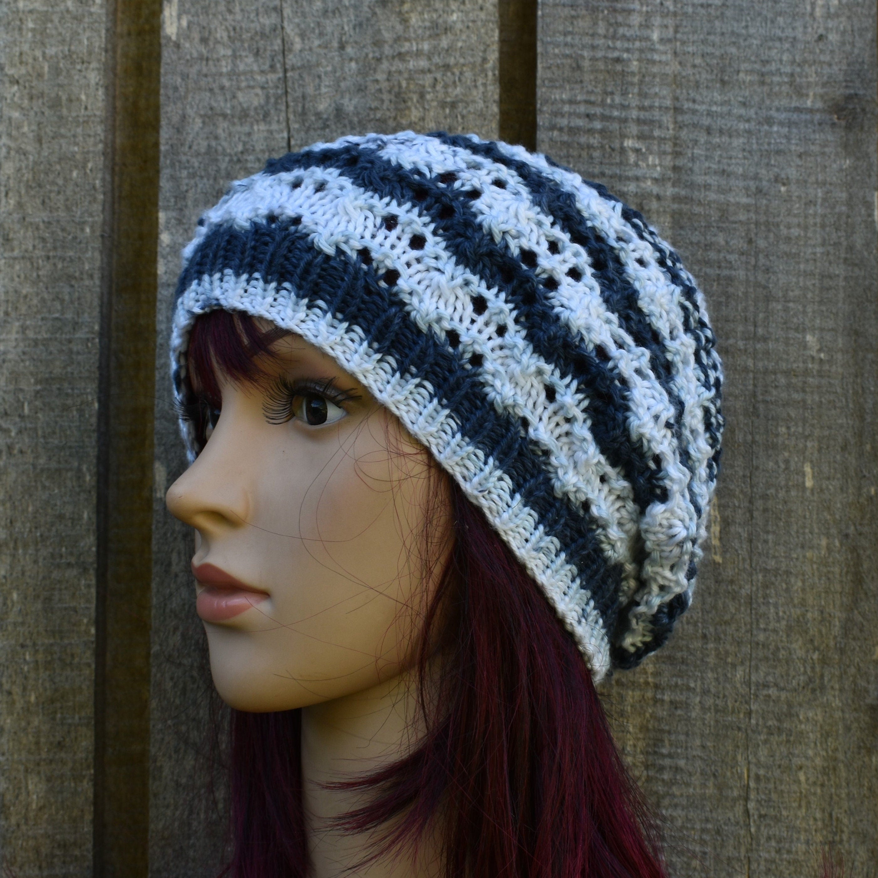 Mannequin head wearing a striped crochet hat against a wooden background