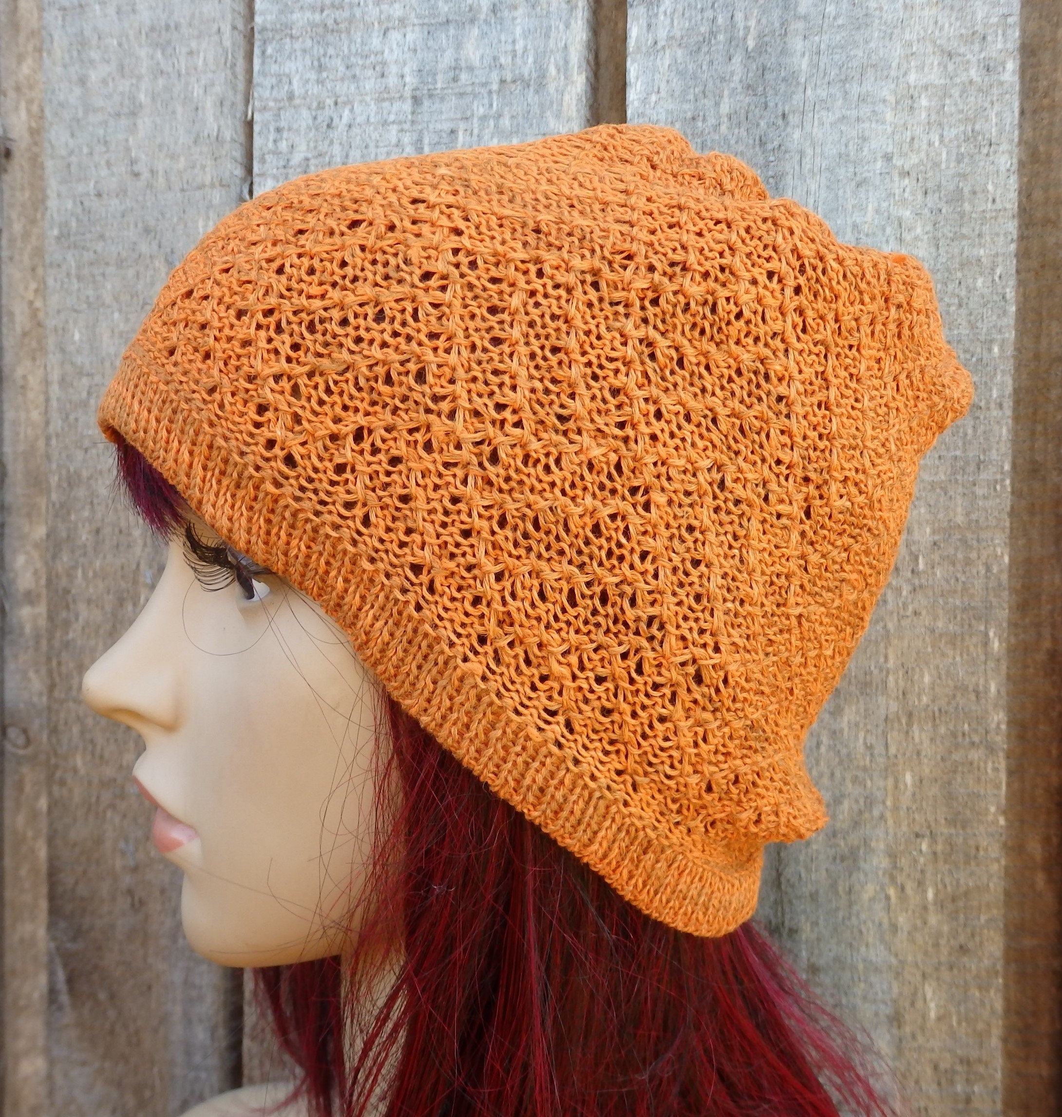 Orange knitted beanie on a mannequin head against a wooden background