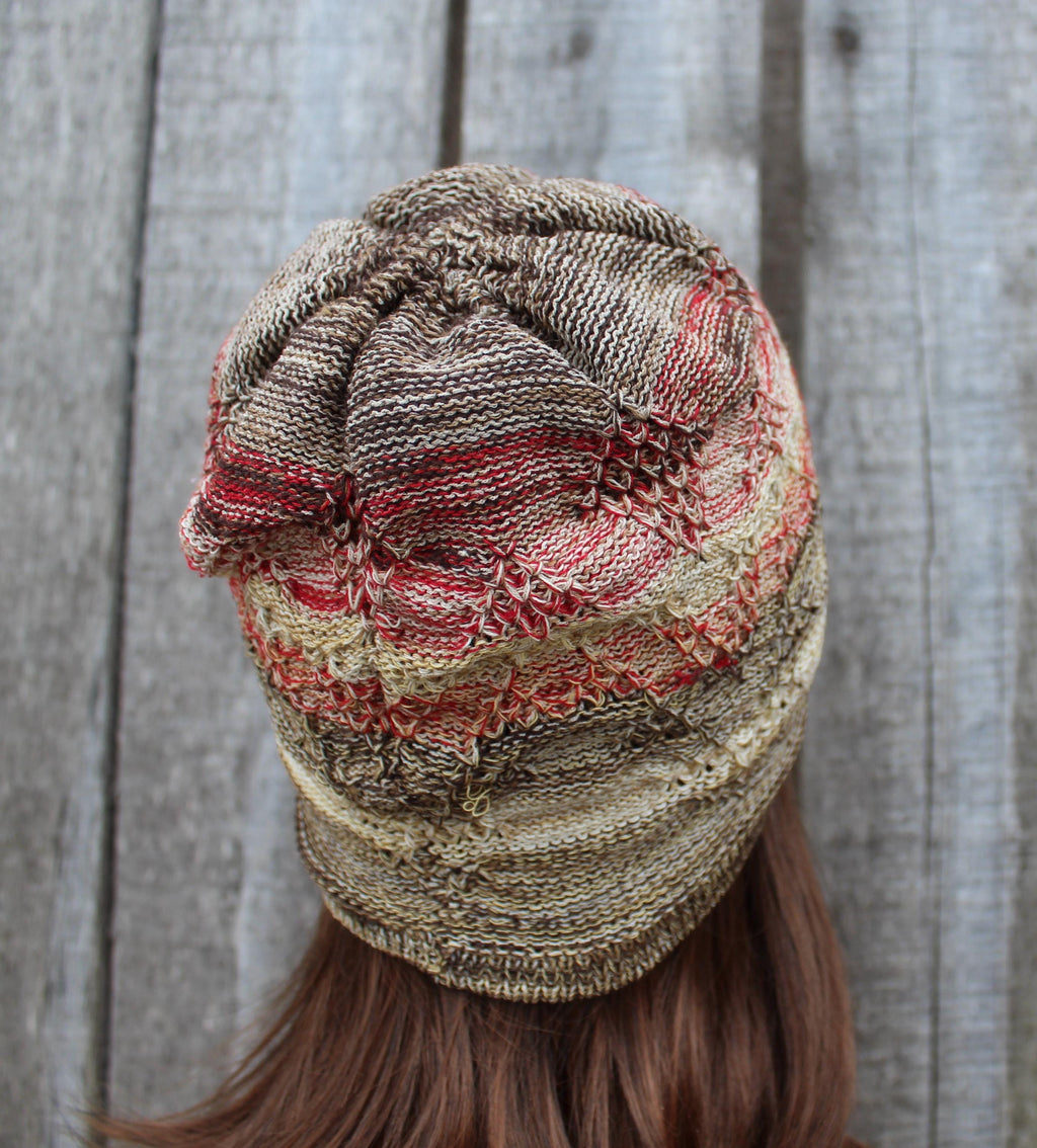Knitted beanie with a textured pattern worn by a person against a wooden background
