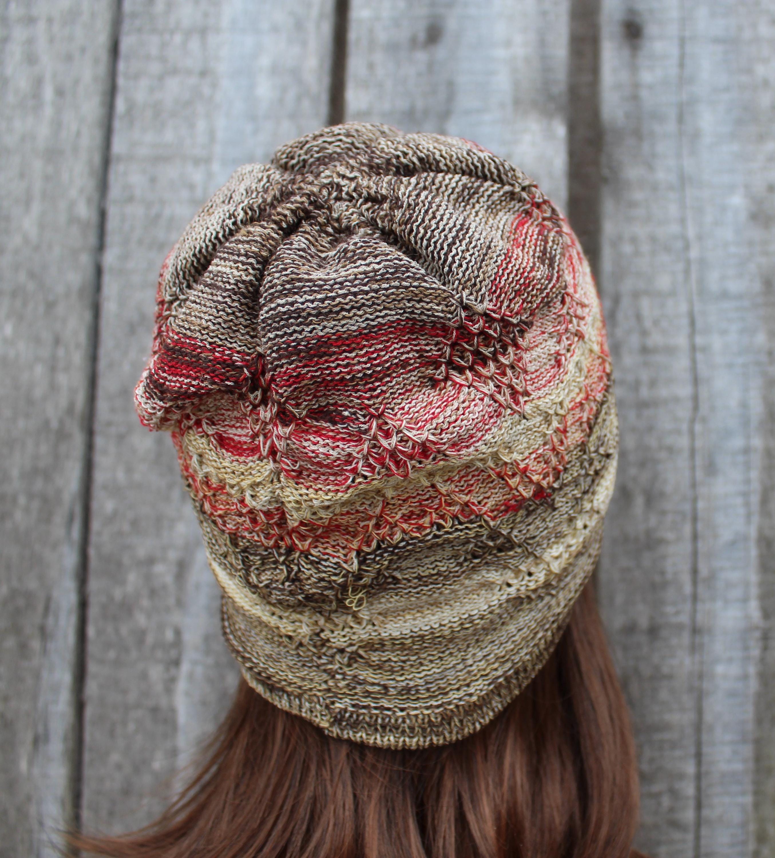 Knitted beanie with a textured pattern worn by a person against a wooden background