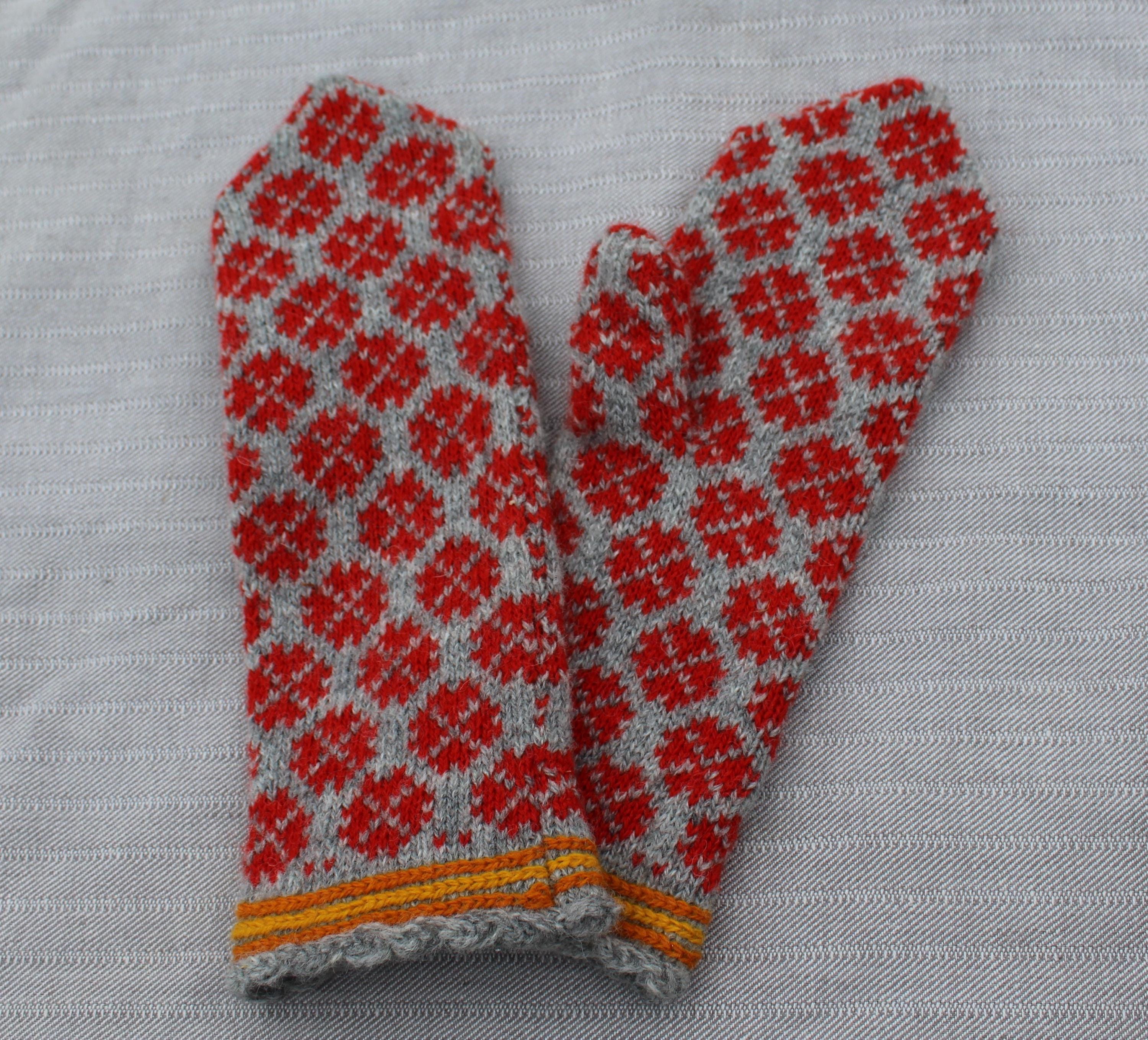 Pair of red and gray patterned mittens on a light gray background