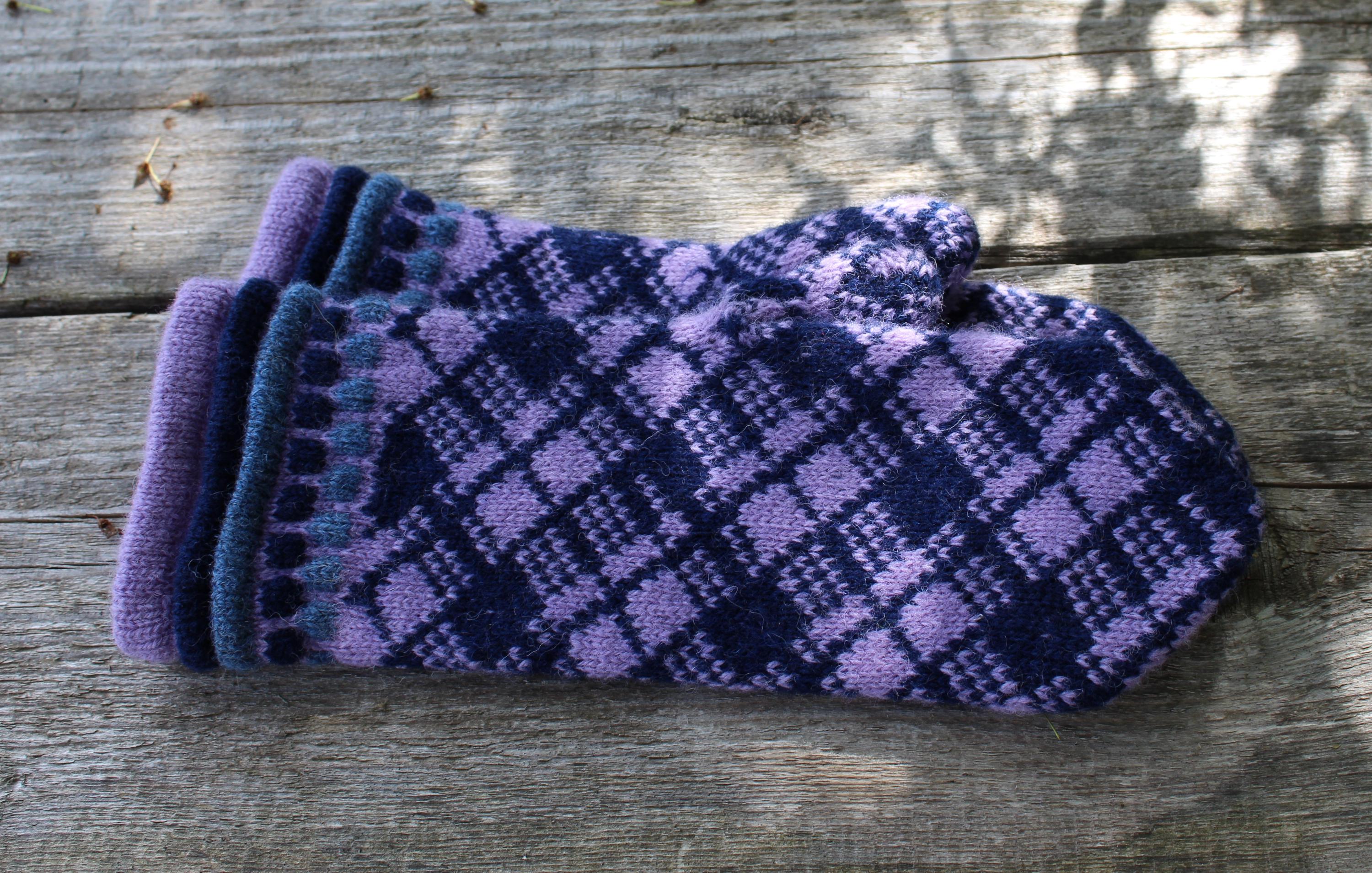Pair of purple and blue checkered mittens on a wooden surface