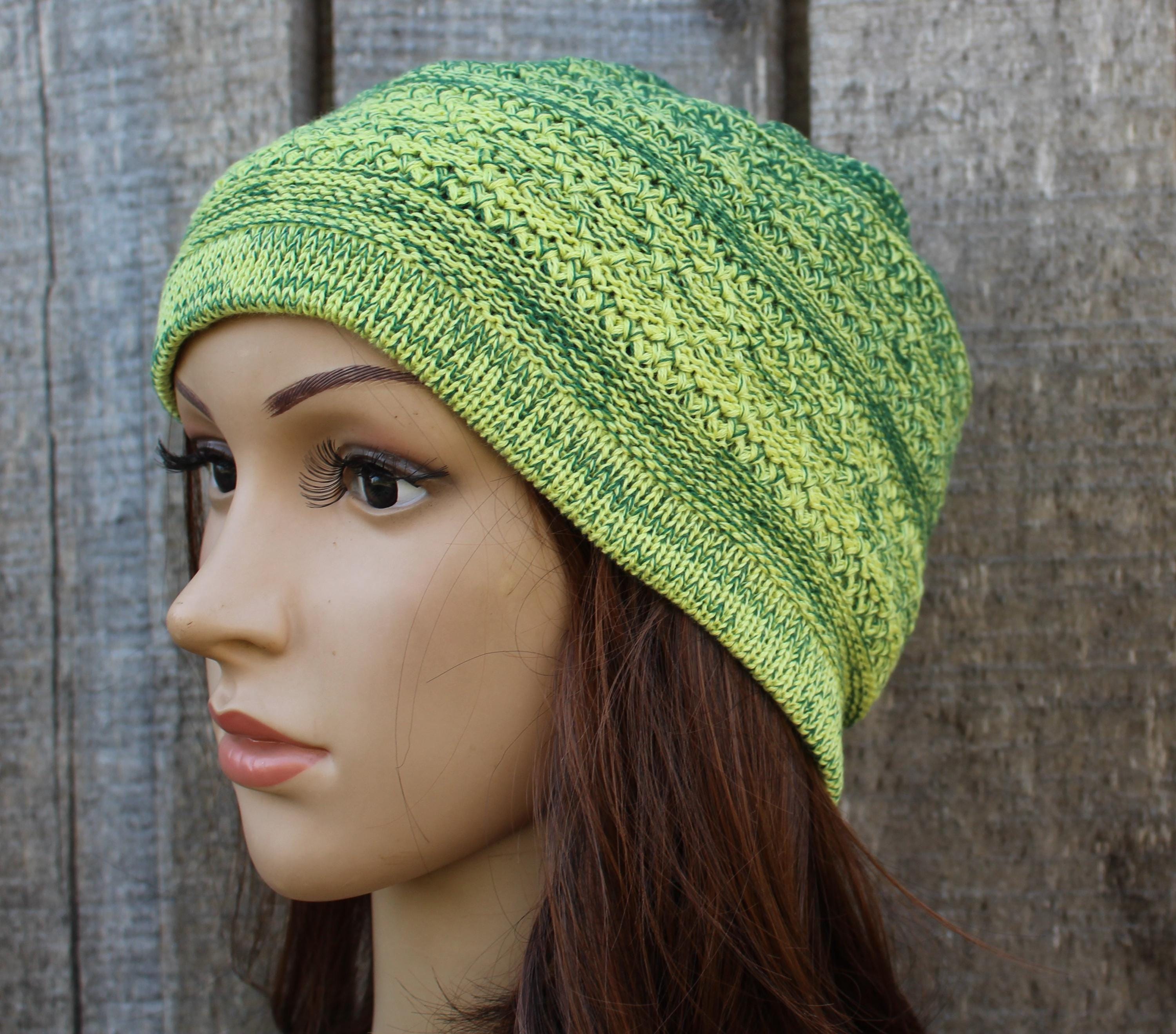 Green knitted beanie on a mannequin head against a wooden background