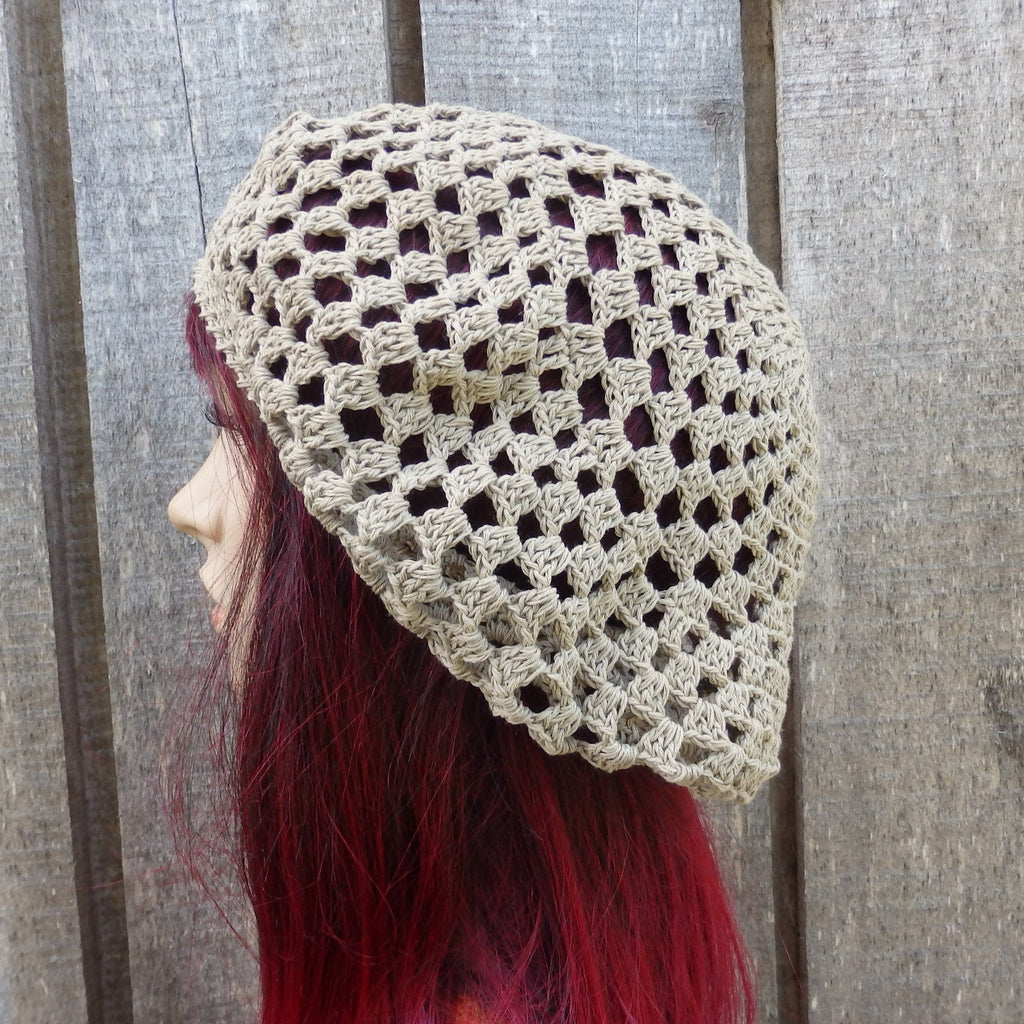 Person wearing a beige crochet hat against a wooden background
