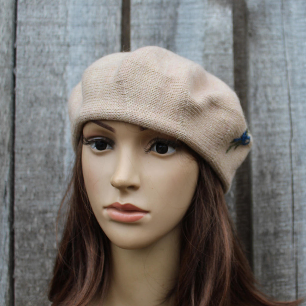 Mannequin head wearing a beige knit cap against a wooden background